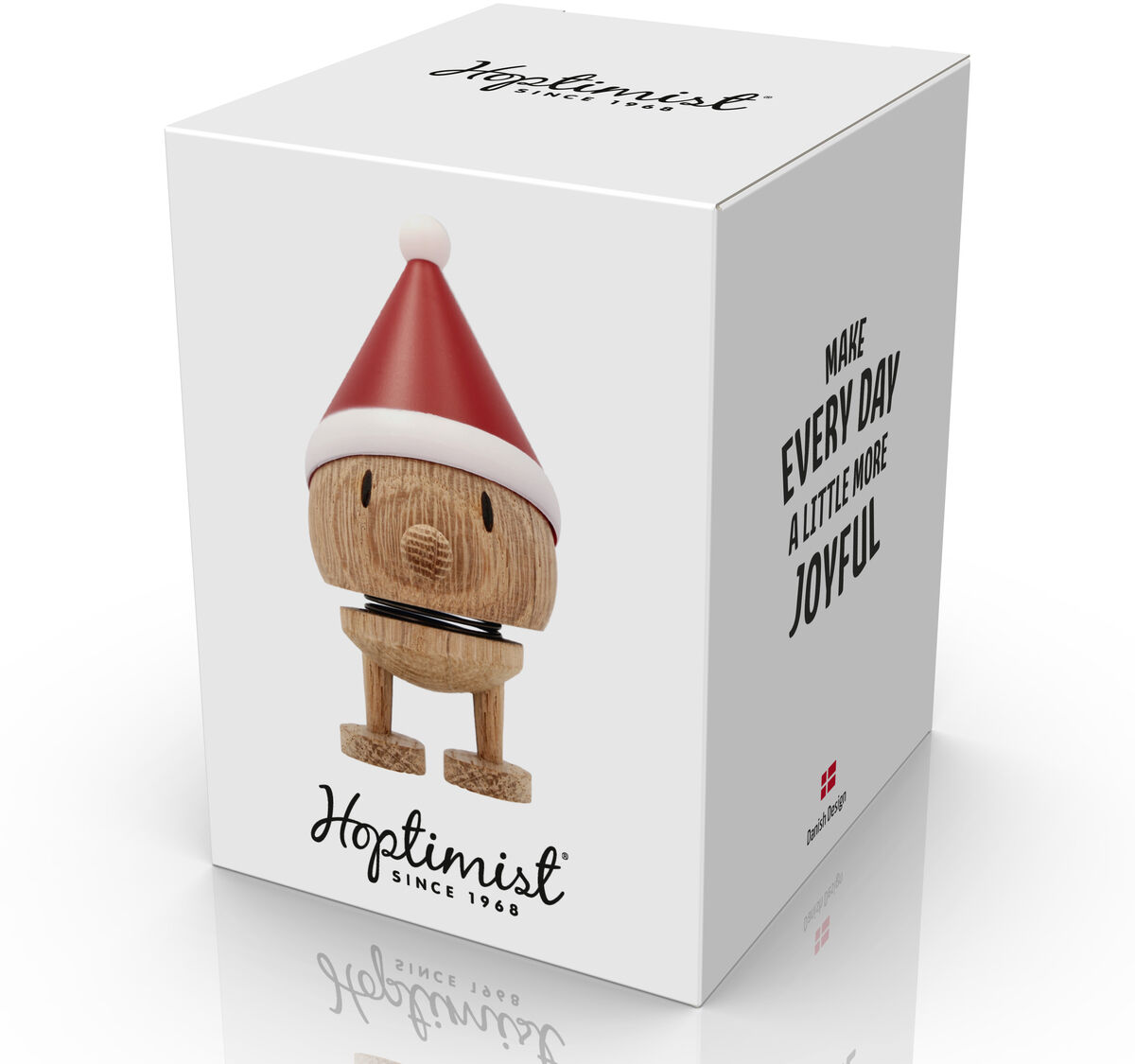 Die Verpackung zeigt die Figur Hoptimist Elf Bumble aus Eiche mit roten Nikolausmütze. Die Box ist weiß, modern gestaltet und trägt den Spruch "Make every day a little more joyful". Unten ist das Hoptimist-Logo prominent platziert.