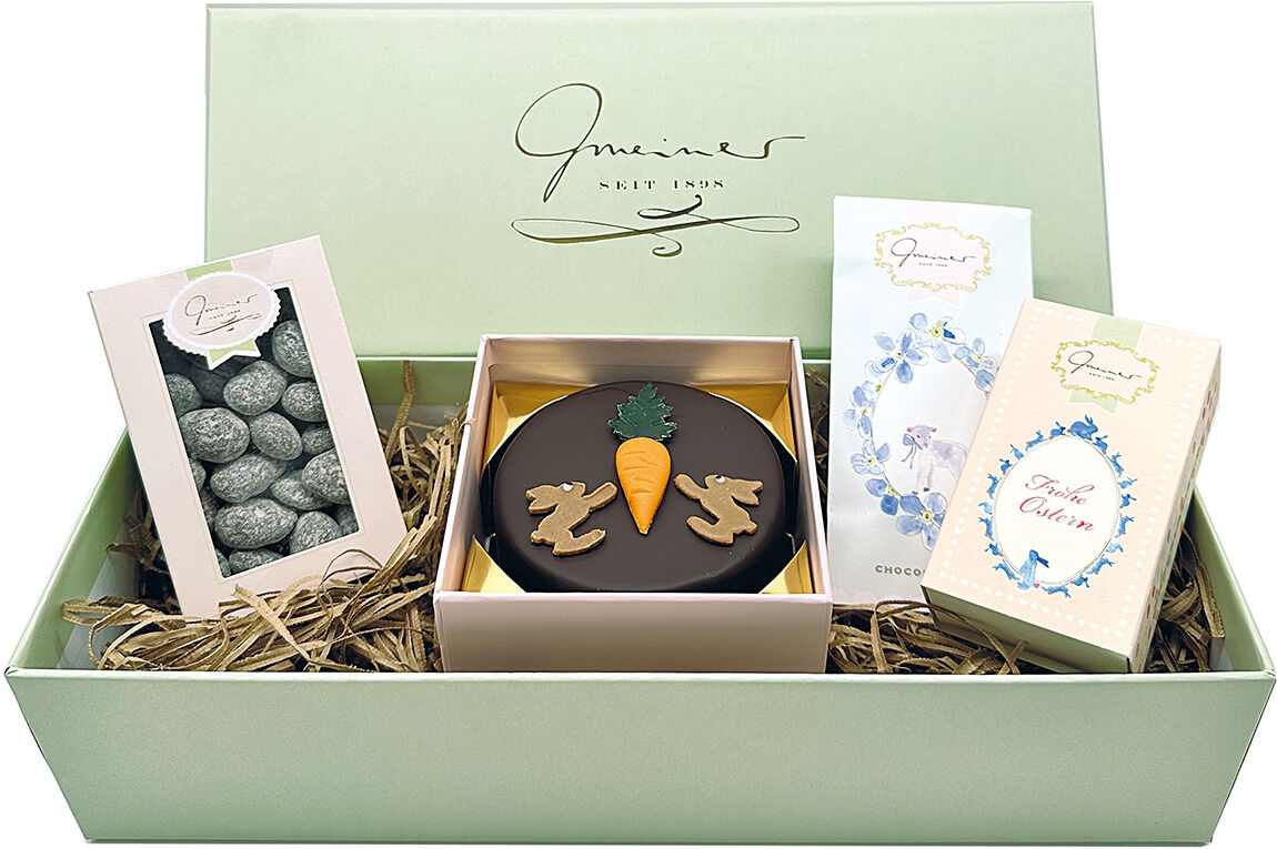 Geschenkbox 'Frohe Ostern' mit verschiedenen Süßigkeiten, darunter Pralinen und Schokolade, in einer grünen Verpackung mit dekorativen Karotten- und Hasenmotiven.