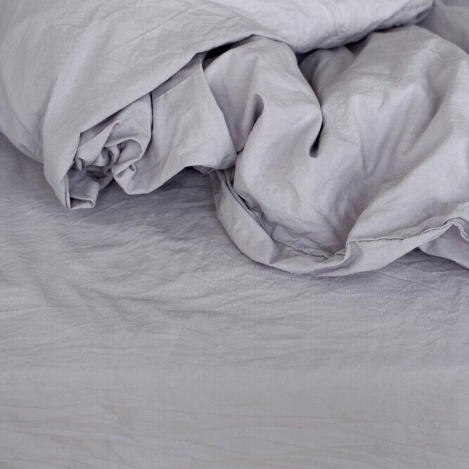 Eine hellgraue Bettwäsche mit einem minimalistischen, weichen Design, das ideal für ein gemütliches und modernes Schlafzimmer ist.