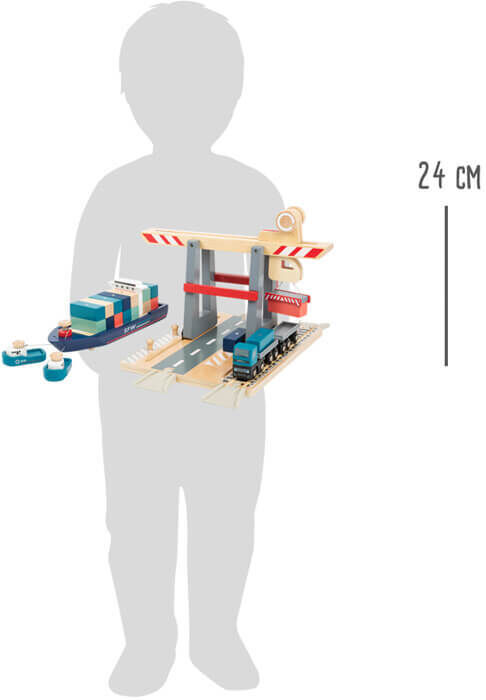 Ein Container Terminal mit Zubehör als Spielzeug für Kinder. Das Set besteht aus einem Holzterminal, Containern und einem Zug. Das Terminal ist überwiegend in Blau, Rot, Weiß und Grau gefärbt. Ein Kind hält das Spielzeug und zeigt die Größe des Sets neben einer Höhenangabe von 24 cm.