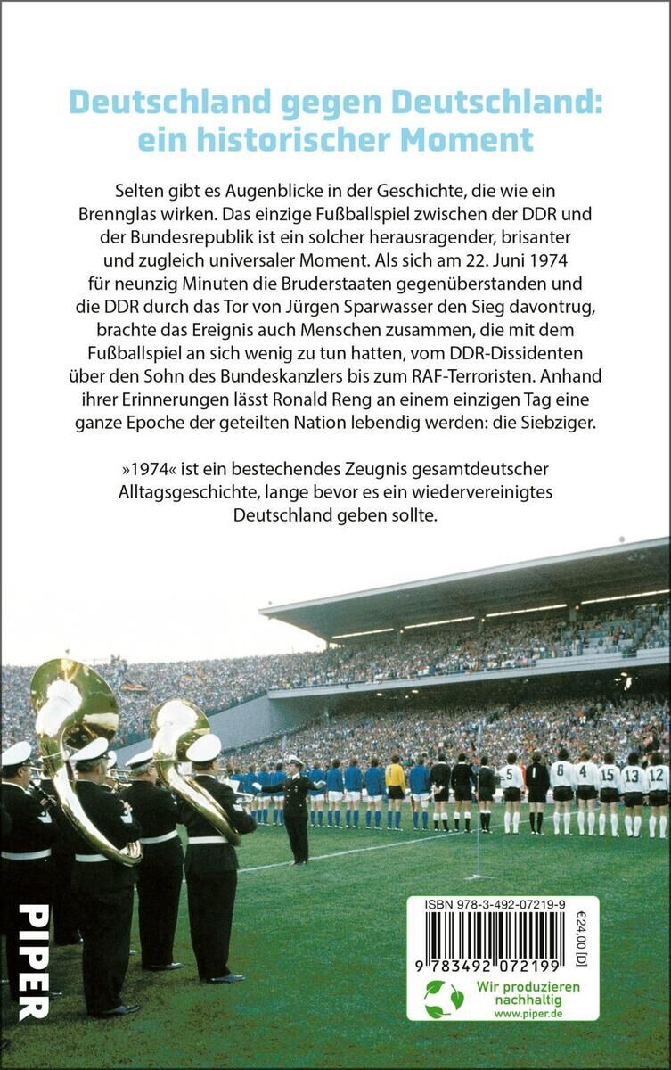 Buchcover von 'Reng, R: 1974 - Eine deutsche Begegnung', das ein Fußballspiel zwischen DDR und BRD auf einem grünen Spielfeld zeigt, mit Spielern in weißen und blauen Trikots und Zuschauern auf der Tribüne im Hintergrund.