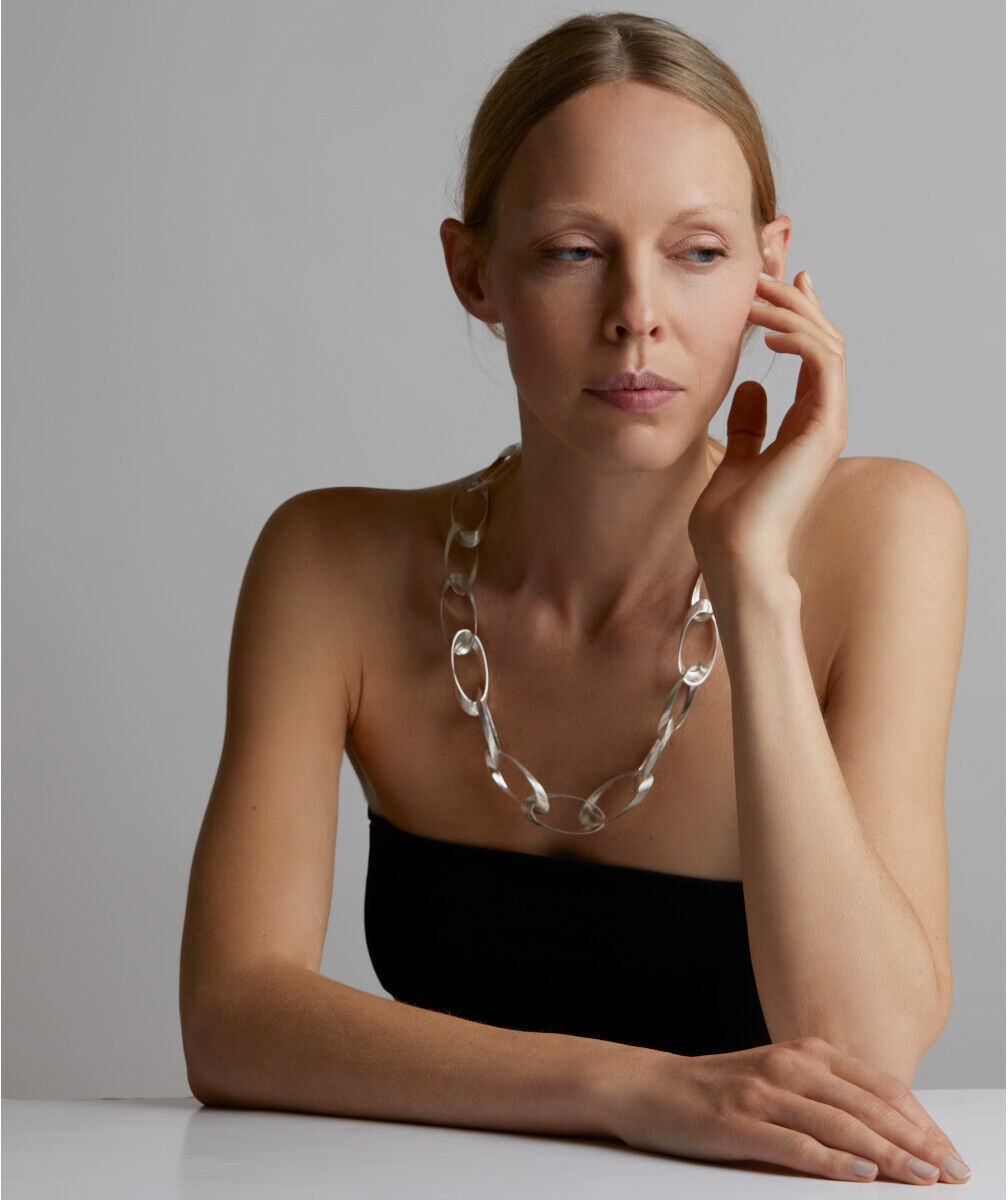 Frau trägt ein durchsichtiges Collier und ein schwarzes trägerloses Oberteil.