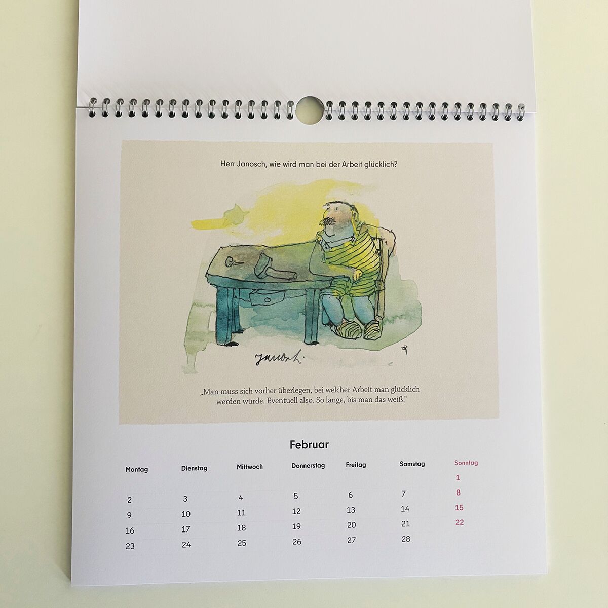 Der Wondrak-Kalender 2026 ist ein Wandkalender mit Spiralbindung, der humorvolle Cartoons und gezeichnete Szenen zeigt. Das sichtbare Februarblatt präsentiert eine farbig illustrierte Figur an einem Schreibtisch mit einem nachdenklichen Zitat. Unterhalb befindet sich eine Monatsübersicht mit den Wochentagen auf Deutsch. Die Gestaltung wirkt freundlich und künstlerisch. Das Produkt eignet sich zur Terminplanung und sorgt für humorvolle Momente im Alltag.