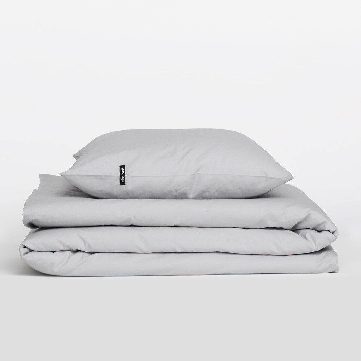Stapel aus grauer Bettwäsche »Pure«, bestehend aus einem Kissenbezug und einem gefalteten Bettbezug, vor einem weißen Hintergrund.
