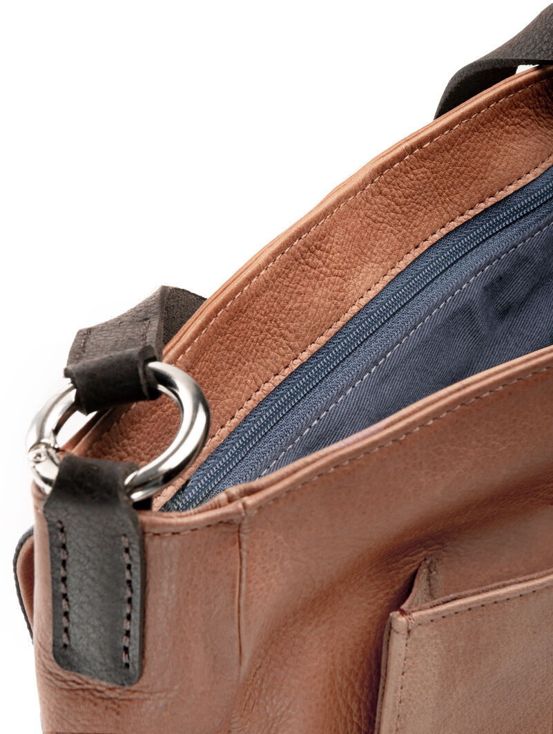 Nahaufnahme einer Slingbag aus Leder mit brauner Außenfläche, schwarzem Schulterriemen und blauen Fächern mit Reißverschluss.