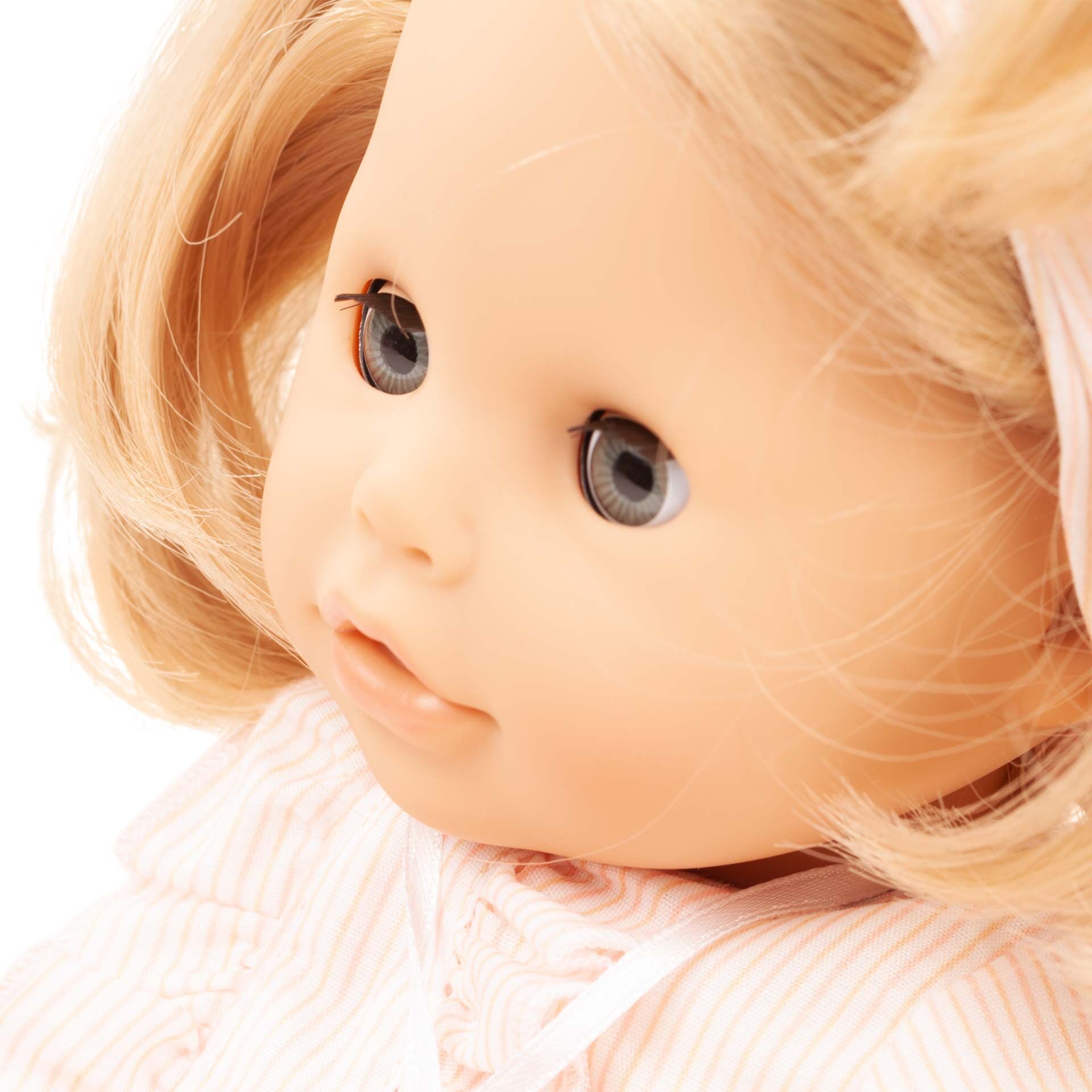 Nahaufnahme einer Badepuppe mit weichen, blonden Haaren, rosa gestreifter Kleidung und neutralem Hintergrund. Die Puppe trägt ein Haarband und wirkt detailreich gestaltet. Geeignet als Kinderspielzeug und Geschenk.