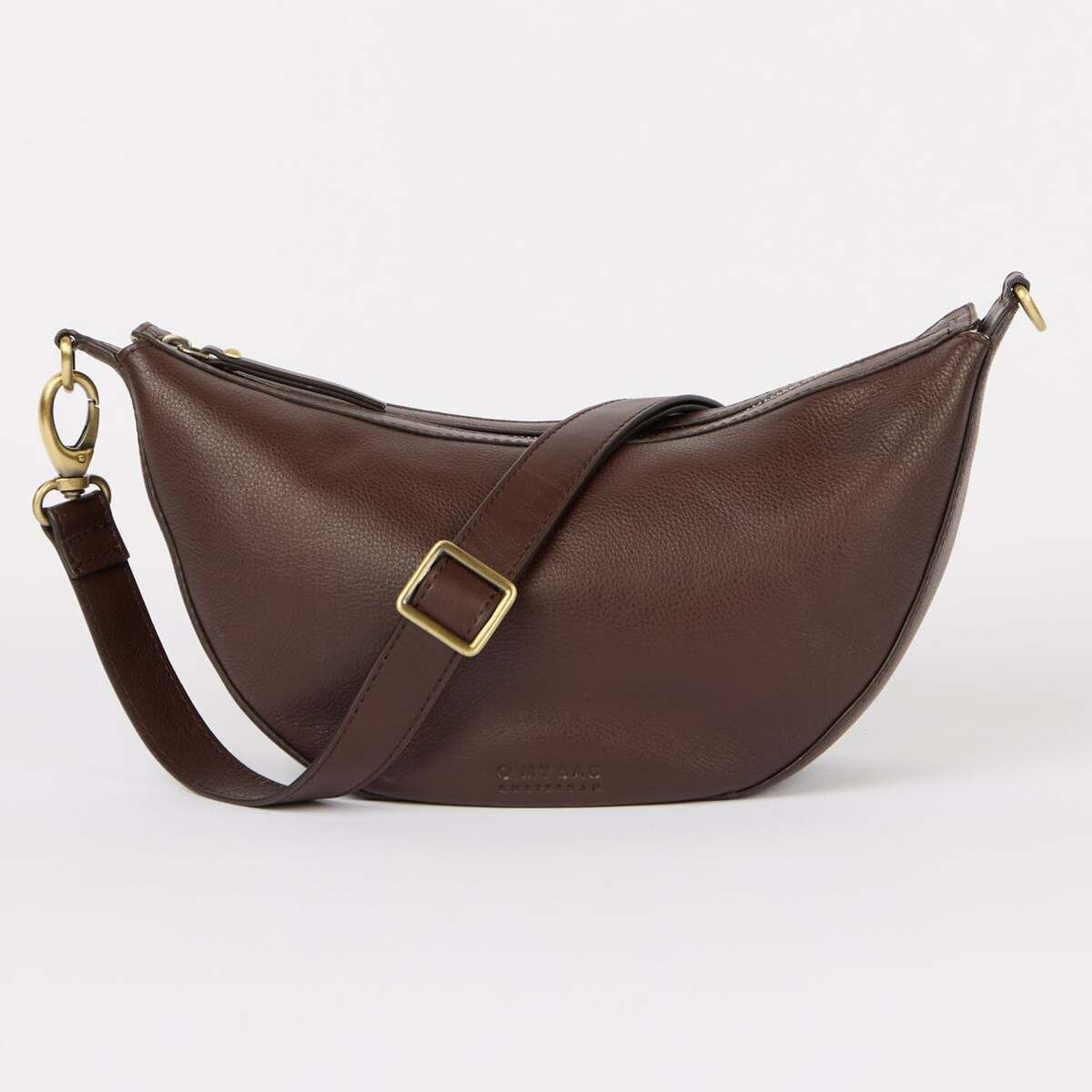 Braune halbmondförmige Umhängetasche mit verstellbarem Gurt und goldfarbenen Metallelementen, fotografiert vor einem neutralen Hintergrund. Das schlichte, minimalistische Design macht die Tasche vielseitig kombinierbar und eignet sich für verschiedene Anlässe.