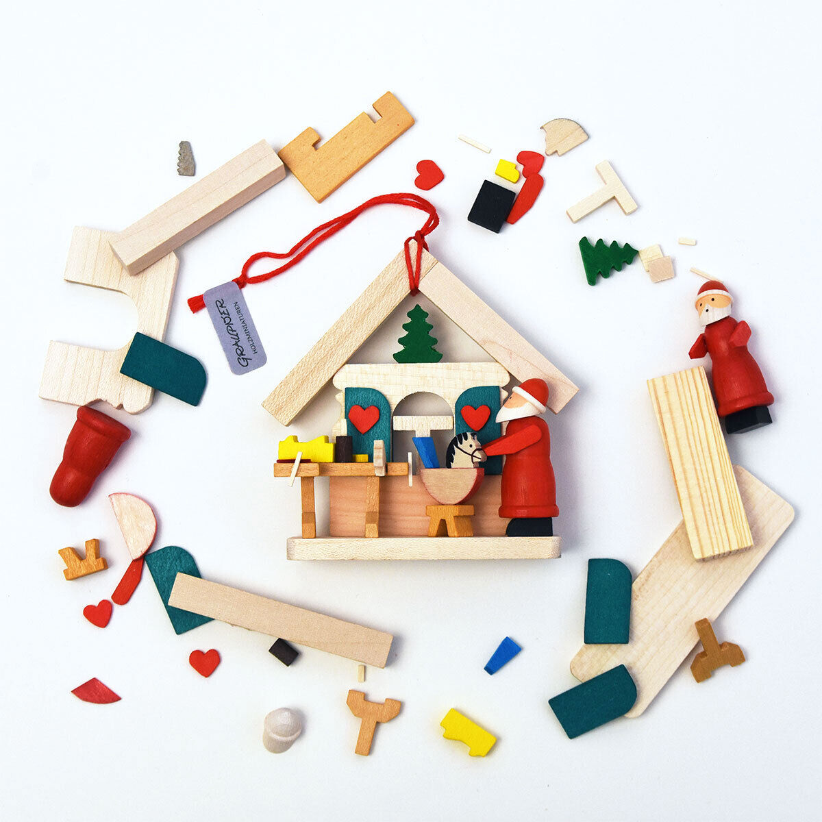 Ein 3-teiliges Baumschmuck Geschenk-Set »Weihnachtsmannhäuser« aus Holz, bestehend aus einer Hausdekoration und mehreren kleinen, bunt bemalten Teilen, darunter ein Weihnachtsmann und Bausteine. Ideal für festliche Weihnachtsdekoration und als Geschenk.