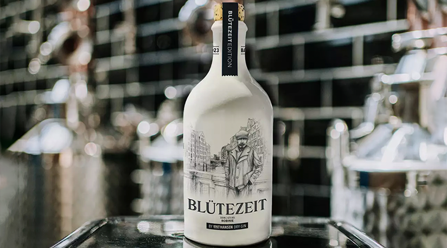 Weiße Flasche mit Aufdruck 'BLÜTEZEIT' und Illustration eines Mannes in Anzug vor Gebäuden, Sonderedition Gin