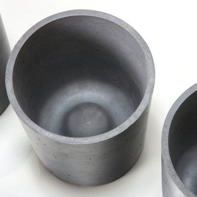 Drei zylindrische Blumentöpfe aus grauem Beton in minimalistischem Design, nebeneinander auf einer hellen Oberfläche platziert.