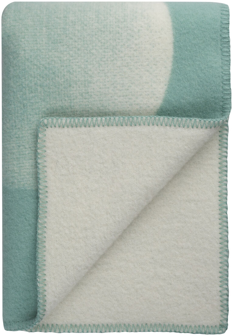 Hellgrüne und weiße Lammwolldecke »MOON«, elegant gefaltet, weicher und kuscheliger Stoff für Gemütlichkeit zu Hause.