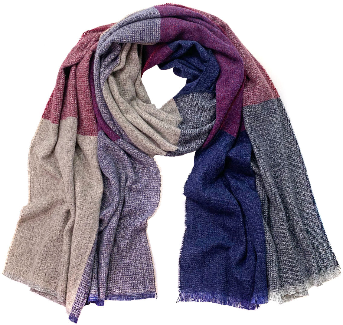 Ein Wollschal Melina, der aus unterschiedlichen Farbblöcken besteht, darunter Beige, Rosa, Violett, Blau und Grau. Der Schal wirkt weich und kuschelig, ideal für kalte Herbst- und Wintertage.