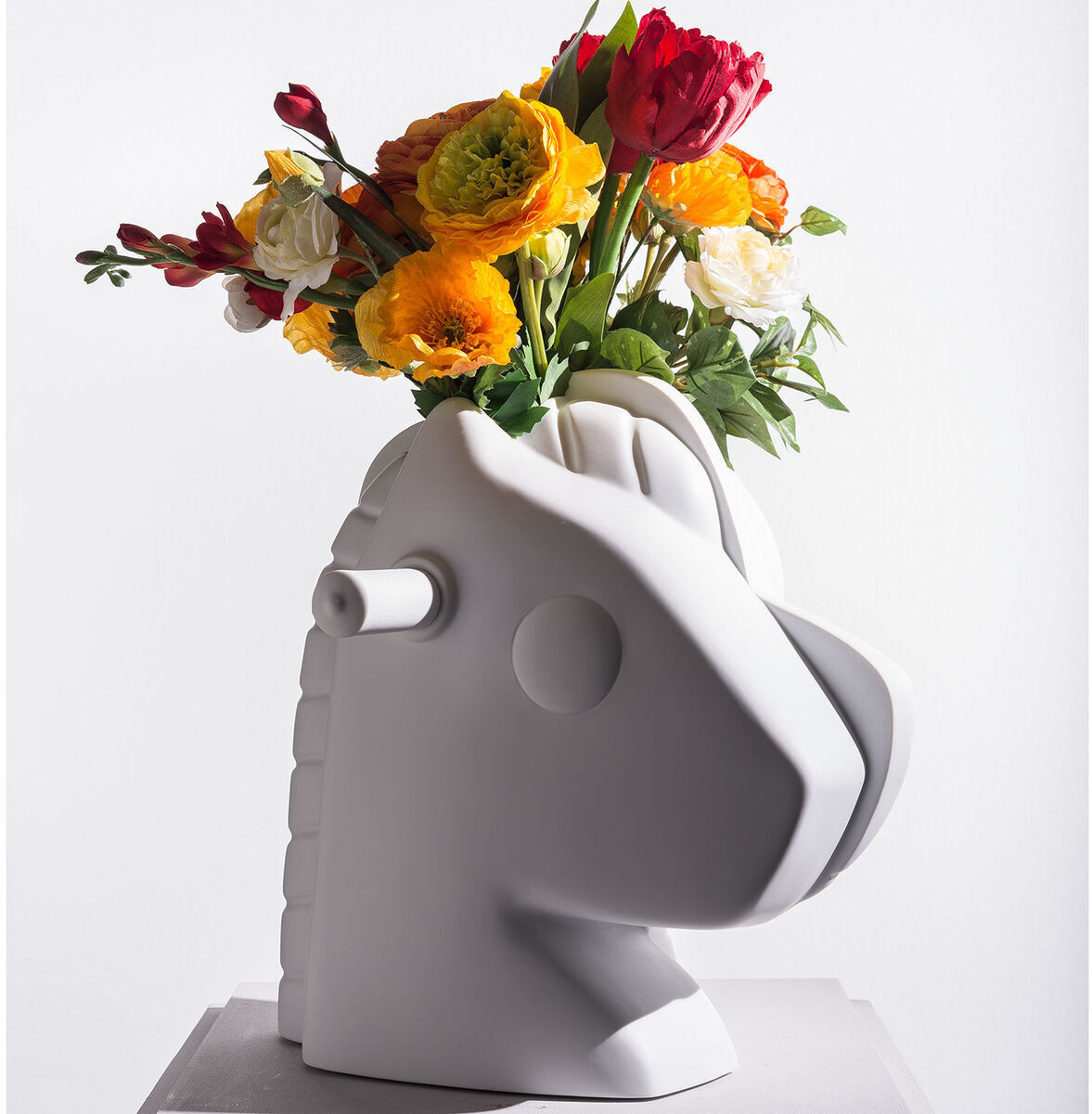 Skulptur von Jeff Koons namens »Split-Rocker«, 2012. Das Kunstwerk stellt einen weißen, stilisierten Pferdekopf dar, der mit bunten Blumen wie roten, gelben und weißen Blüten dekoriert ist.