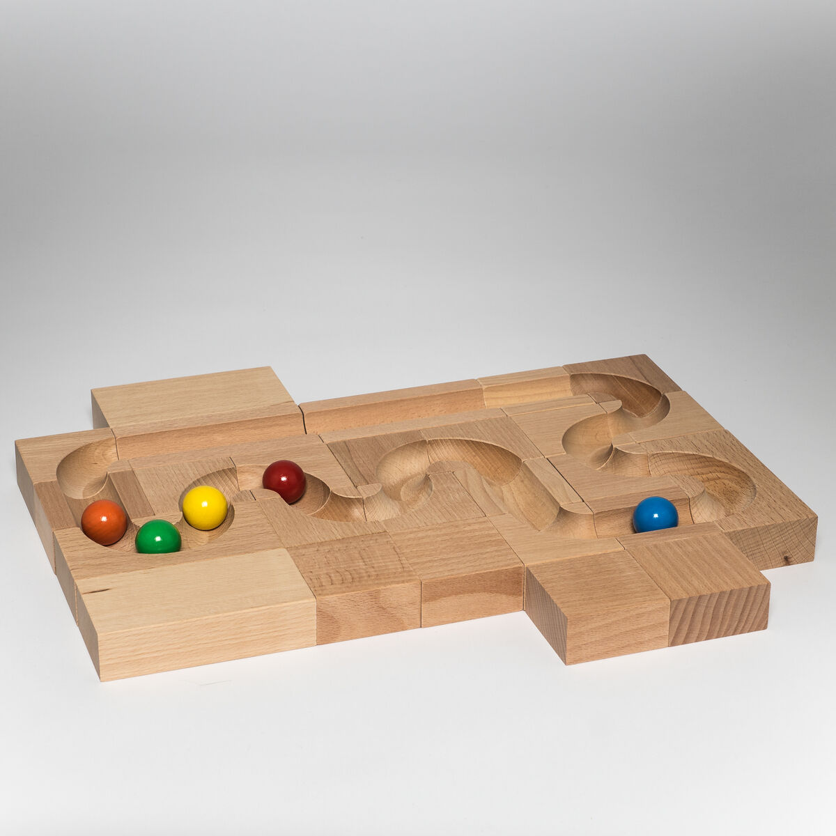Eine Kugelbahn aus Holz mit einem geschwungenen Parcours und bunten Murmeln in Rot, Gelb, Blau und Grün.