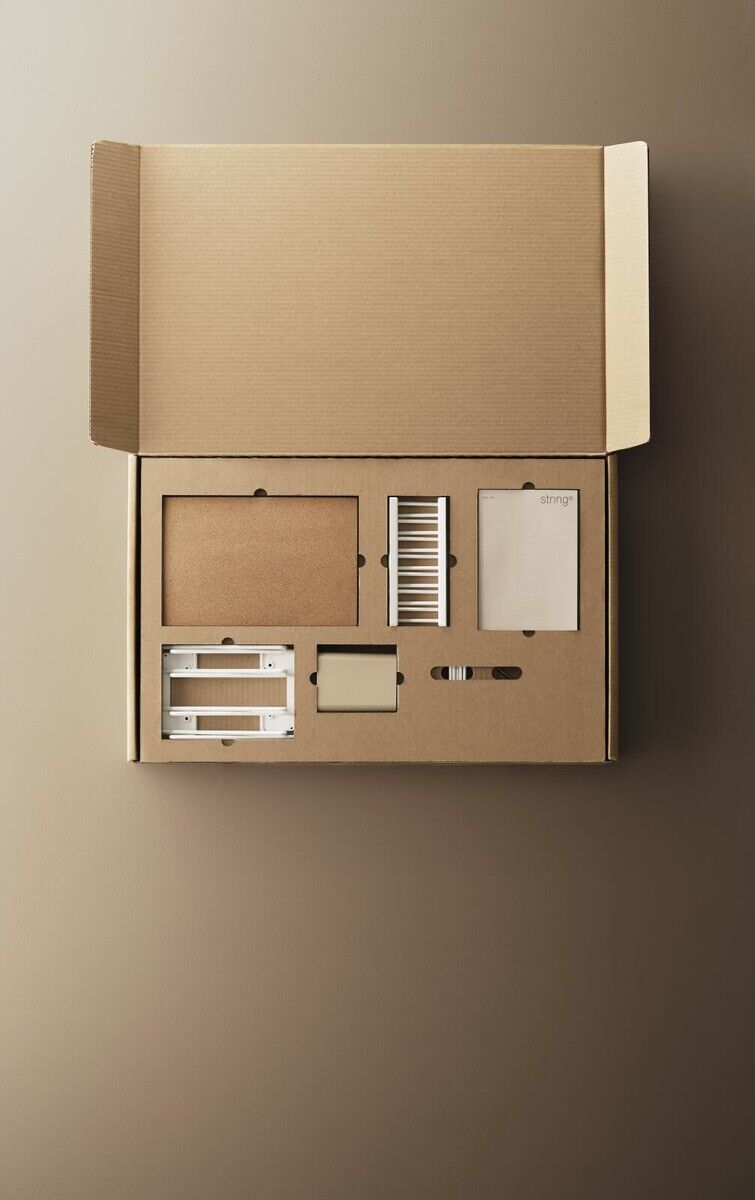 Ein offener Karton mit den Einzelteilen des String Küchenregals, einschließlich Regalböden, Halterungen und Montagematerialien. Der Karton und die Teile sind in neutralen Brauntönen gehalten.