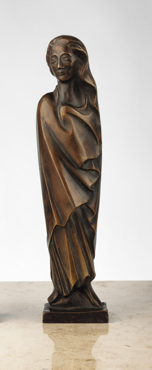 Eine Bronzeskulptur von Ernst Barlach aus dem Jahr 1931. Sie zeigt eine abstrakte Frauenfigur, umhüllt von einem fließenden Gewand, als ob sie im Wind steht. Der Ausdruck der Figur ist ruhig, aber entschlossen, was die Bewegung des Windes andeutet.