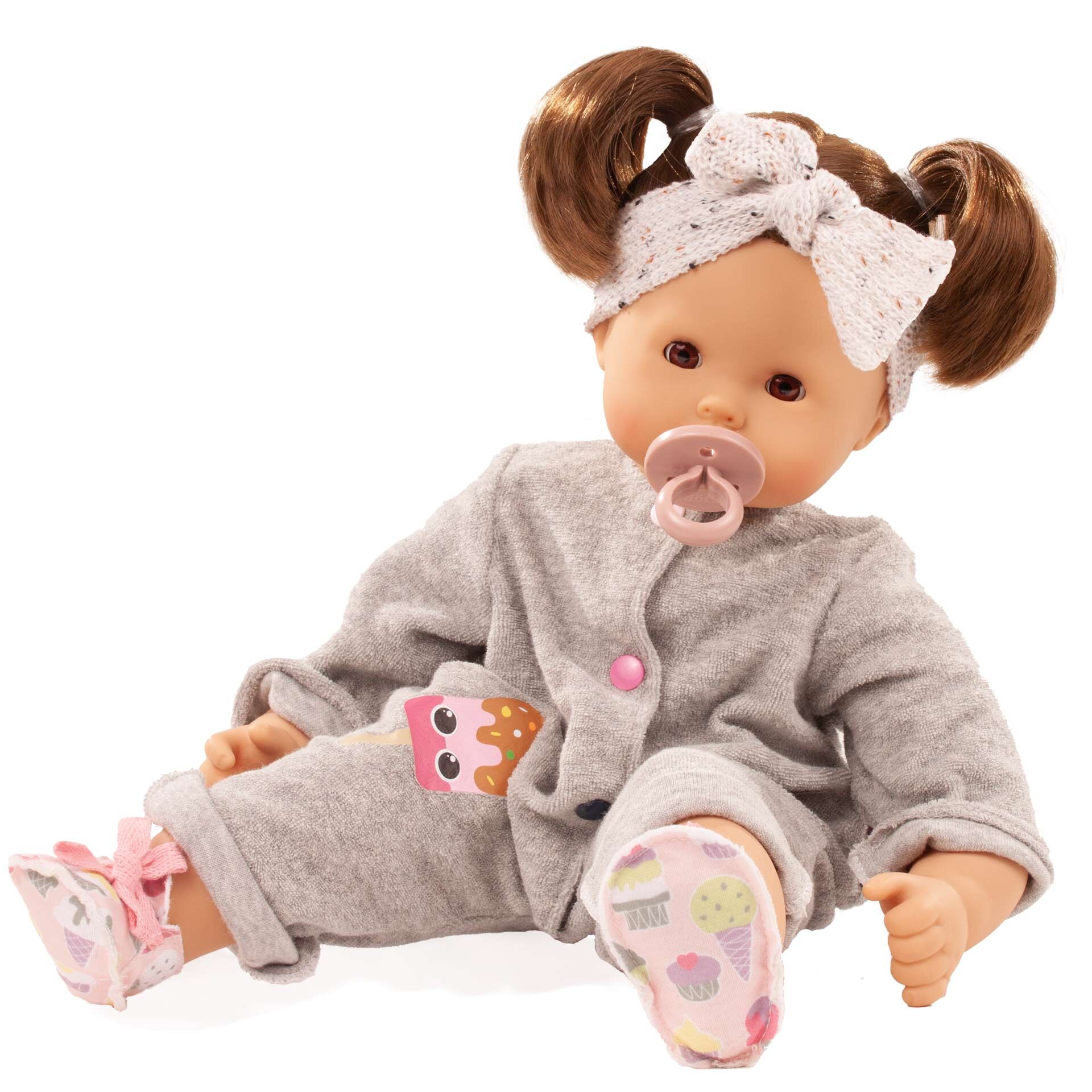 Puppe Maxy Muffin Popsicle sitzt aufrecht, trägt einen grauen Schlafanzug mit Eulenmotiv, rosa Schnuller und eine weiße Schleife im Haar. Die Puppe hat detailreiche Gesichtszüge und weiche Gliedmaßen, ideal als Spielzeug für Kinder.