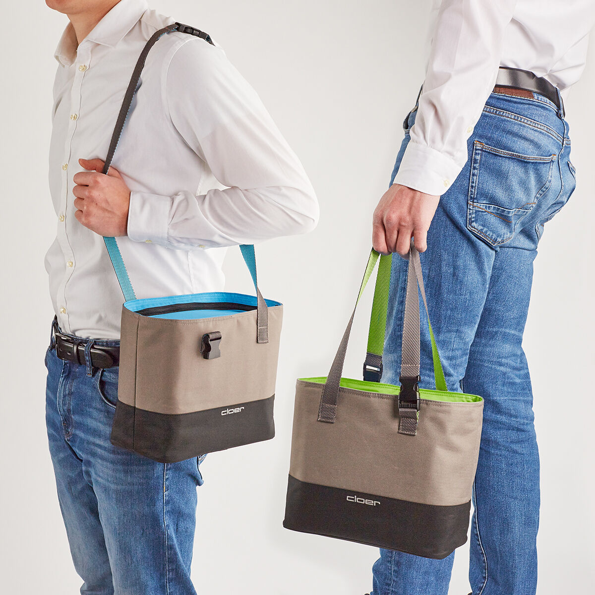 Zwei Männer tragen Lunch-Taschen mit farbigen Elementen an ihren Schultern. Sie tragen beide Jeans und weiße Hemden. Die Taschen haben graue und schwarze Farbtöne mit entweder blauen oder grünen Akzenten.