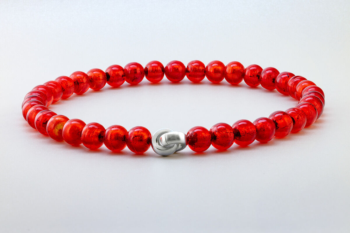 Ein handgefertigtes Murano Collier mit hellroten Glasperlen und einem silbernen Verschluss vor einem weißen Hintergrund.