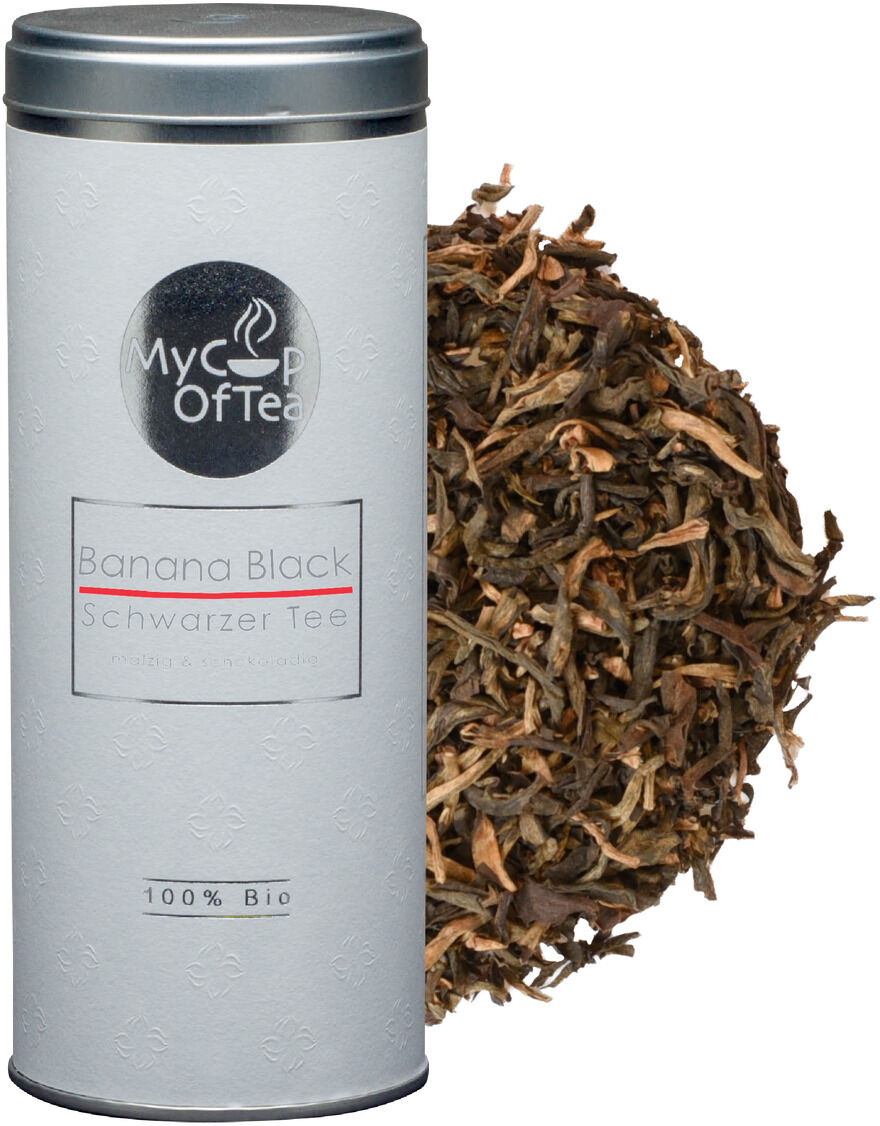 Eine silberne Teedose mit der Aufschrift 'Banana Black Schwarzer Tee' von My Cup Of Tea steht neben einem Haufen losem Teeblättermischung.