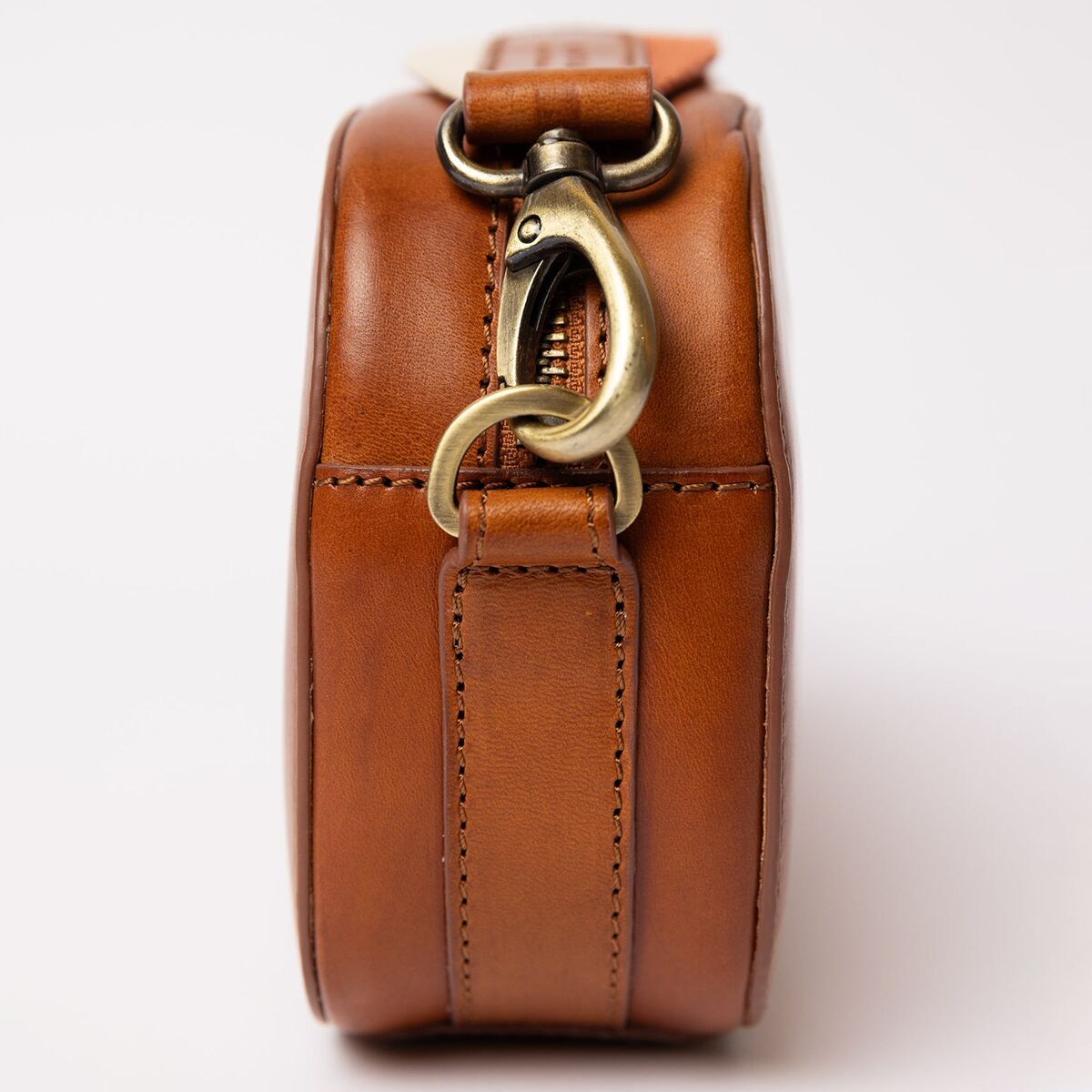 Die Abbildung zeigt eine braune Umhängetasche mit glatter Oberfläche in Lederoptik. Der Fokus liegt auf dem seitlichen Metallverschluss in goldener Farbe. Die Tasche wirkt schlicht und elegant, geeignet für Alltag und besondere Anlässe.