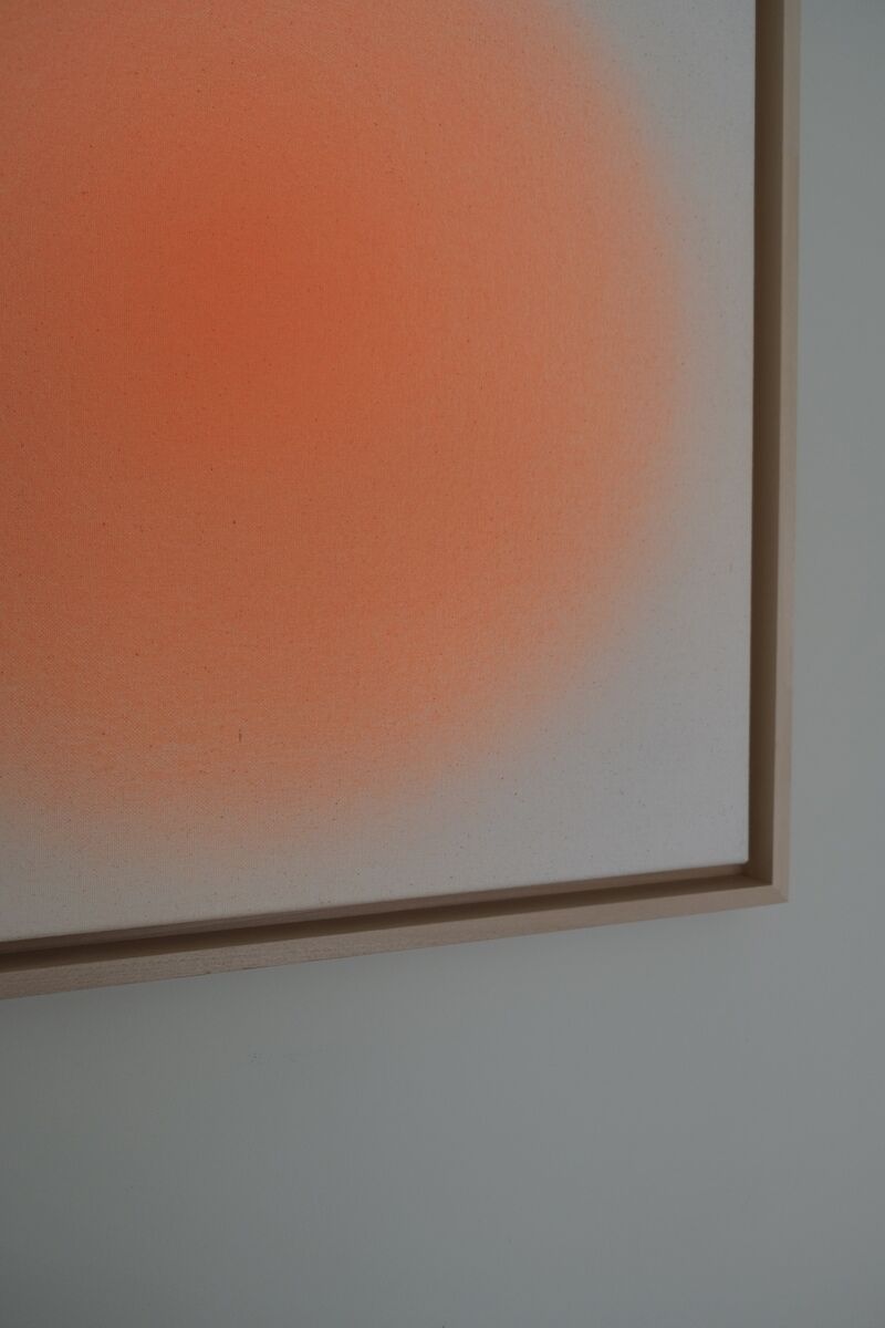Abstraktes Kunstwerk mit einer kreisförmigen Farbverlauf in Orange auf einem weißen Hintergrund, gerahmt in einem schlichten, beigen Rahmen.