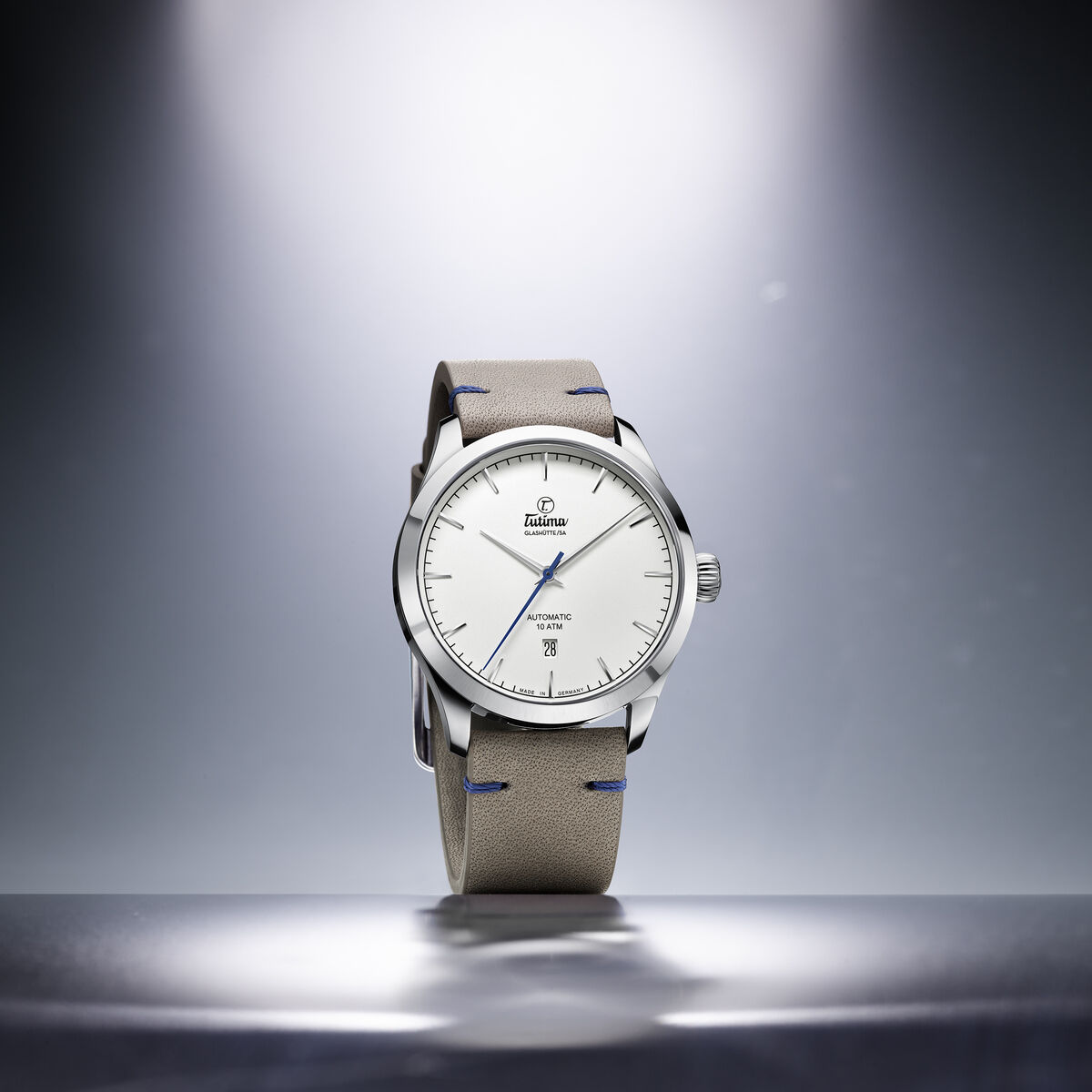 Die ZEIT Sonderedition »Flieger Aero Club« Automatikuhr präsentiert sich mit einem eleganten Edelstahlgehäuse und einem cremefarbenen Lederarmband. Das Zifferblatt ist klar strukturiert mit blauen Akzenten und wird in einem sanften Licht dargestellt.