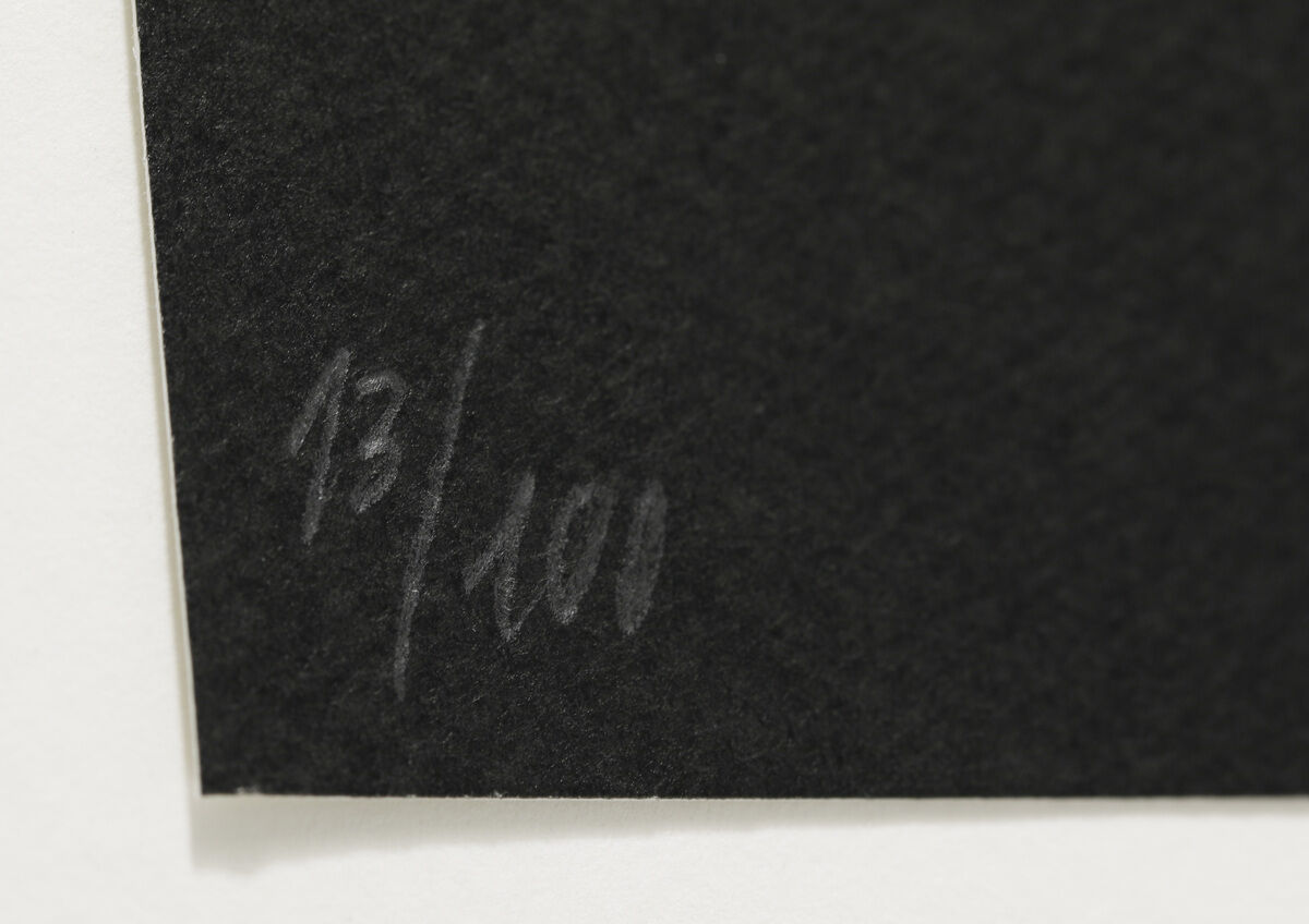 Eine Nahaufnahme einer Kunstwerk-Signatur auf einem schwarz-weißen Kunstdruck mit der Editionnummer 13/100.