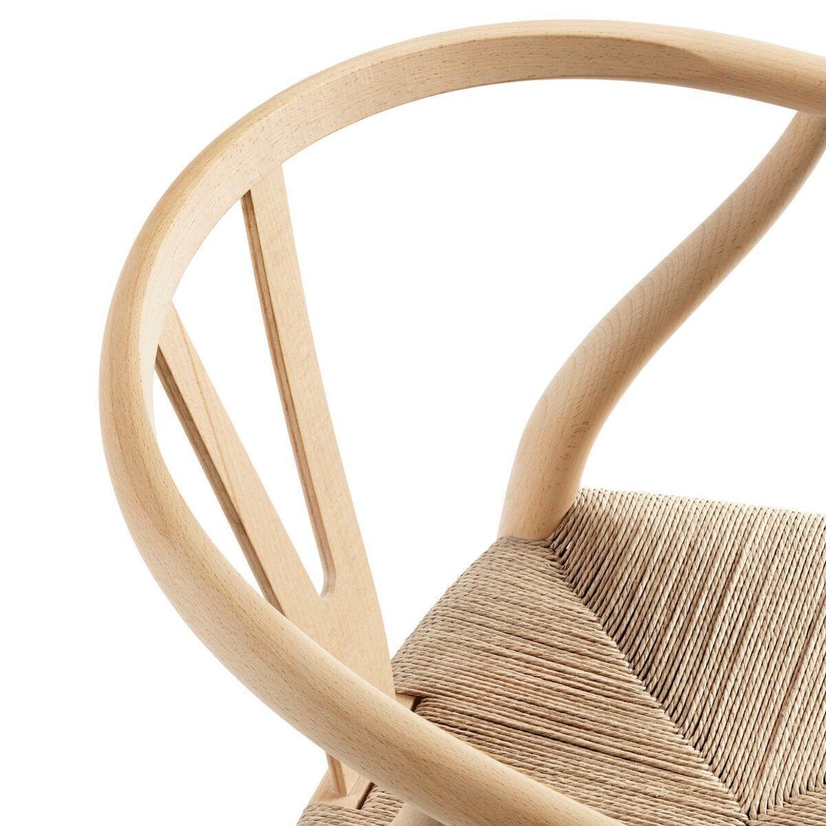 Detailaufnahme der Sitzfläche und Rückenlehne eines Wishbone Chair CH24 von Carl Hansen & Søn. Der Stuhl besteht aus naturbelassenem Holz mit geflochtener Sitzfläche.