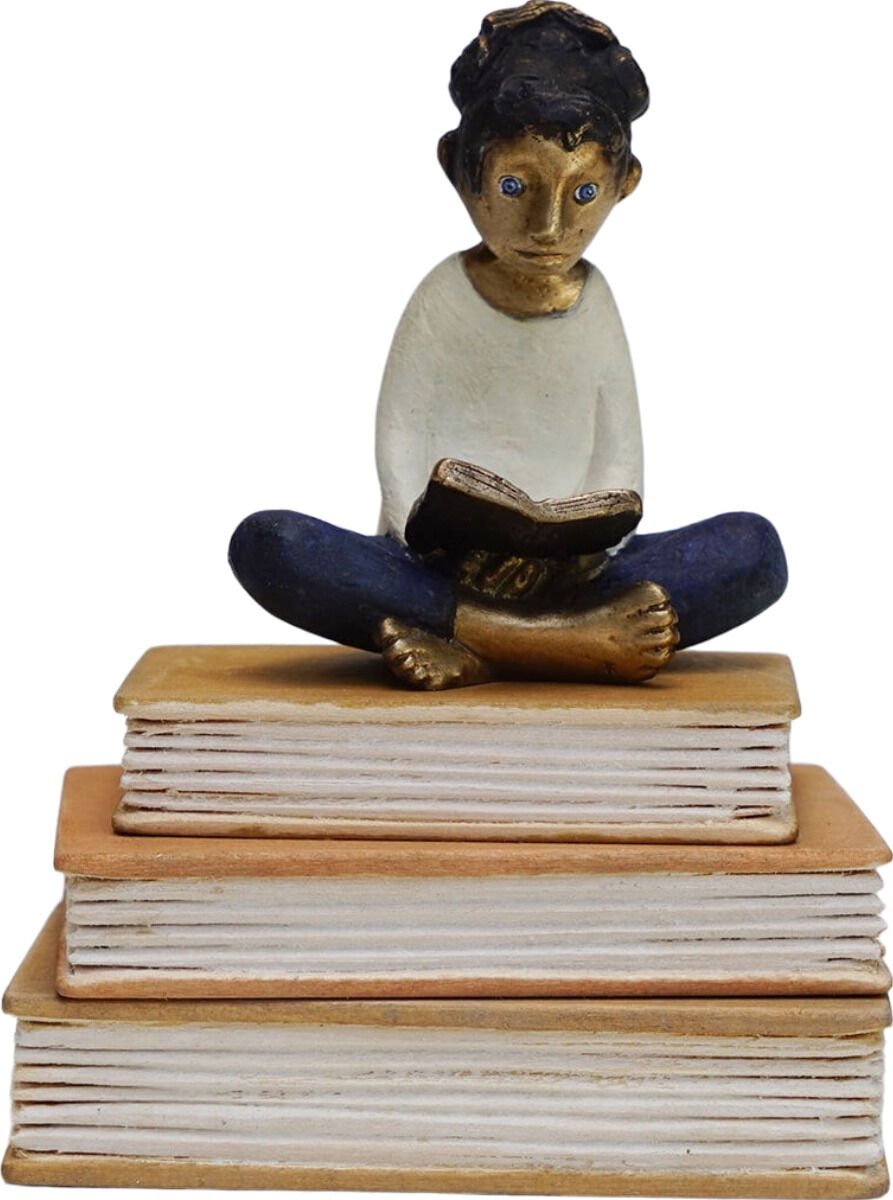 Eine Skulptur von Tamara Suhr in der ZEIT Sonderedition, benannt »LeseReise«. Die Skulptur zeigt eine Figur, die auf einem Stapel von Büchern sitzt und ein Buch liest. Die Figur trägt blaue Hosen und ein weißes Oberteil. Die Bücher sind in erdigen Tönen gehalten.