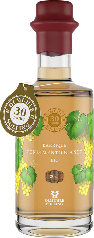Flasche Condimento Bianco Barrique aus der Präsentbox Jubiläumsessige von Ölmühle Solling, transparentes Glas mit goldener Flüssigkeit, beidseitig Traubenillustrationen, braun-roter Verschluss, goldene Jubiläumsplakette „30 Jahre“, Etikett mit weißen Schriften, Bio-Siegel sichtbar.