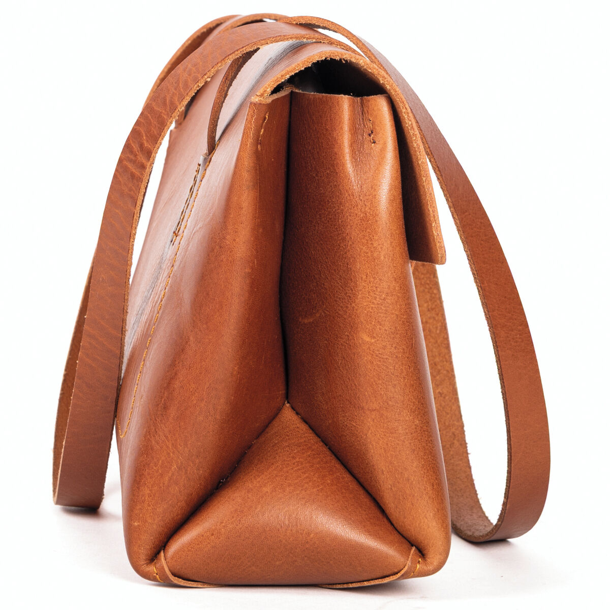 Seitliche Nahaufnahme einer hochwertigen cognacfarbenen Schultertasche aus Kernleder, Marke Harold's Lederwaren, mit klar sichtbarem Trageriemen. Die Tasche steht auf weißem Hintergrund und besticht durch ihr minimalistisches, elegantes Design und glattes Leder.