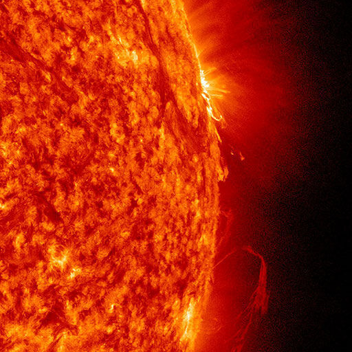 Ein Bild der Sonne, aufgenommen vom Solar Dynamics Observatory der NASA. Die Oberfläche zeigt intensive Sonnenaktivität mit hellen Eruptionen und einer dominierenden roten, orangen und gelben Farbpalette. Der Hintergrund ist schwarz und hebt die energetischen Erscheinungen der Sonnenoberfläche hervor.