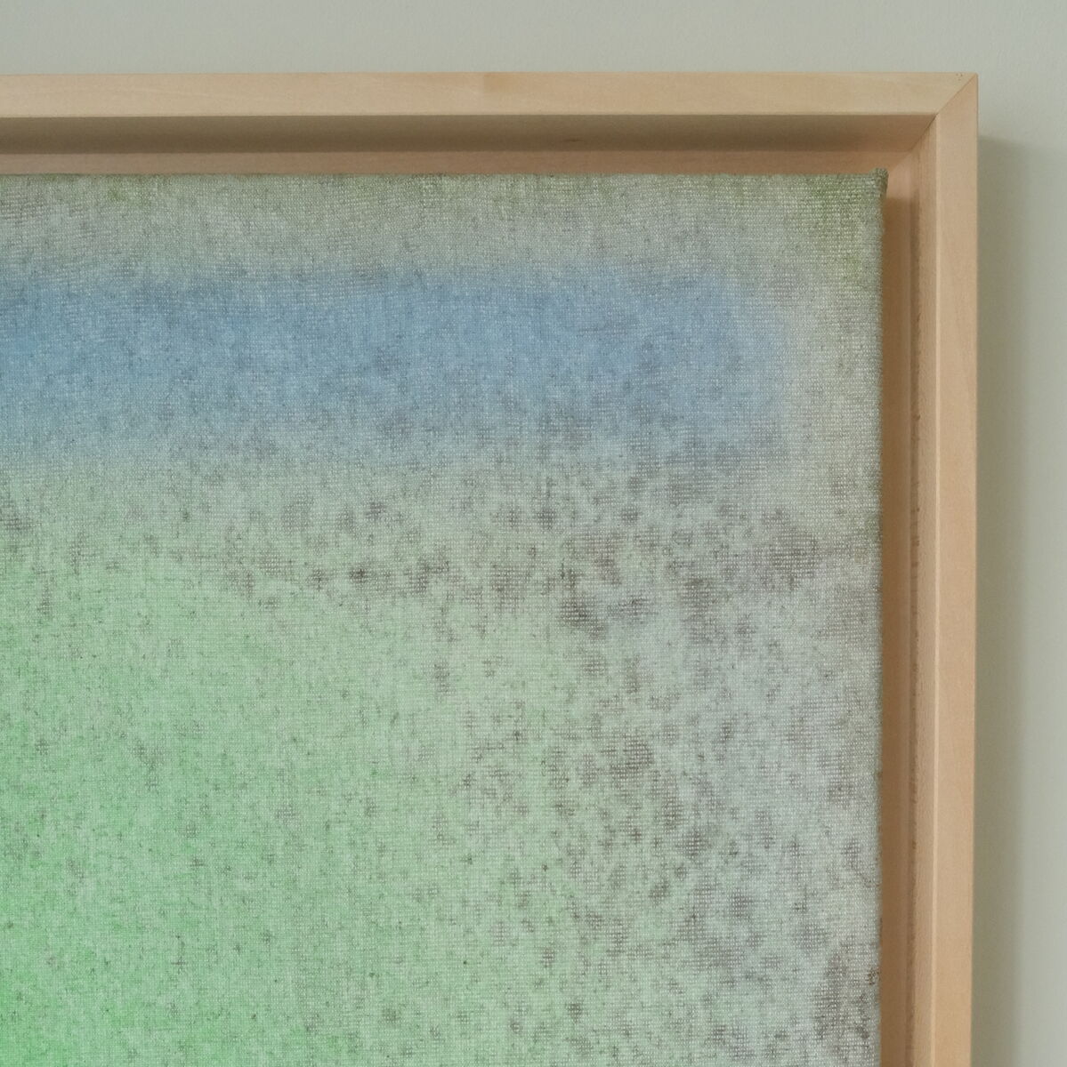 Ein Kunstwerk mit abstrakten Farben, dominierend in Grün und Blau, in einem Holzrahmen präsentiert. Das Bild zeigt einen weichen Übergang der Farben, die beruhigend wirken.