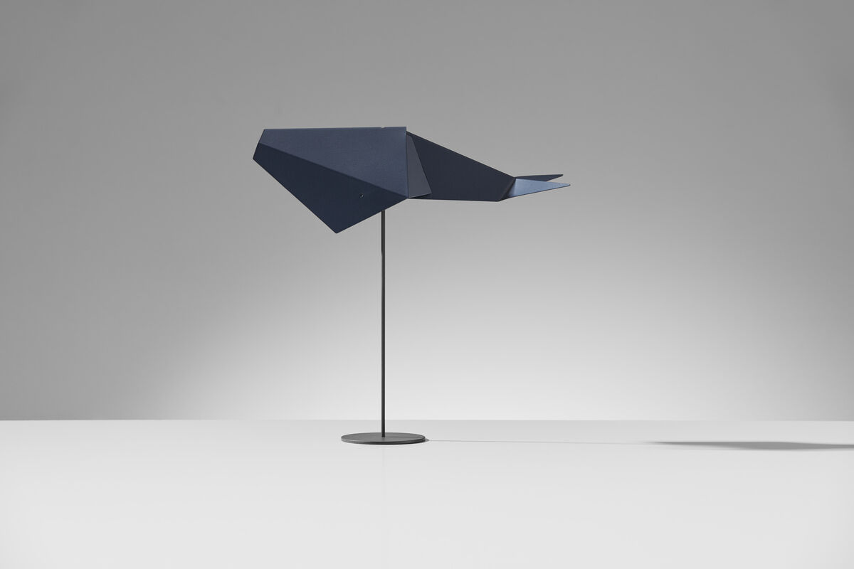 Eine moderne Skulptur namens »Cachalot« in Origami-Optik. Die Skulptur ist Blau mit einem schwarzen Metallständer und steht vor einem grauen Hintergrund. Das Design besticht durch geometrische Formen und eine minimalistische Ästhetik.