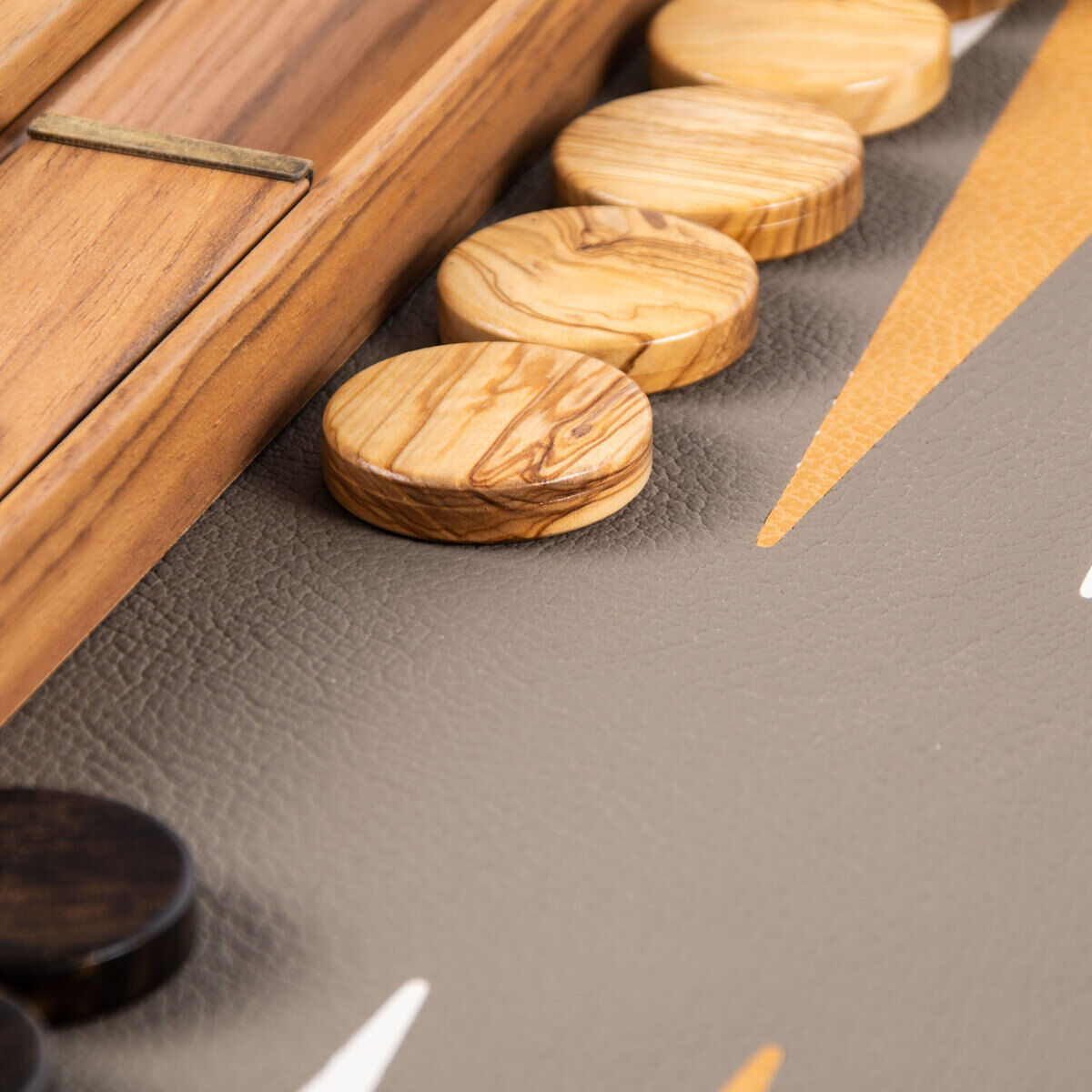 Nahaufnahme eines hochwertigen Backgammon-Spiels in graubeiger Straußenleder-Optik mit holzfarbenen Spielsteinen.