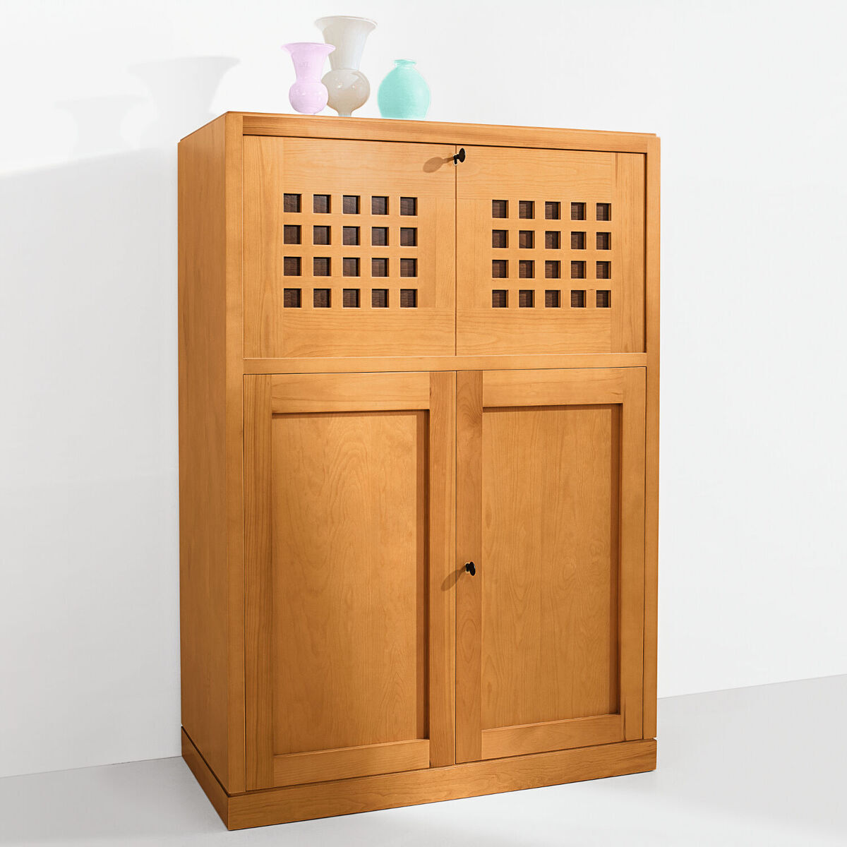 Bild eines modernen, hellbraunen Sekretärs aus Holz von Marktex (Sonderedition) mit oberen Fächern, die Gittertüren aufweisen, und unteren Fächern mit schlichten Türen. Auf dem Möbelstück befinden sich drei pastellfarbene Vasen.