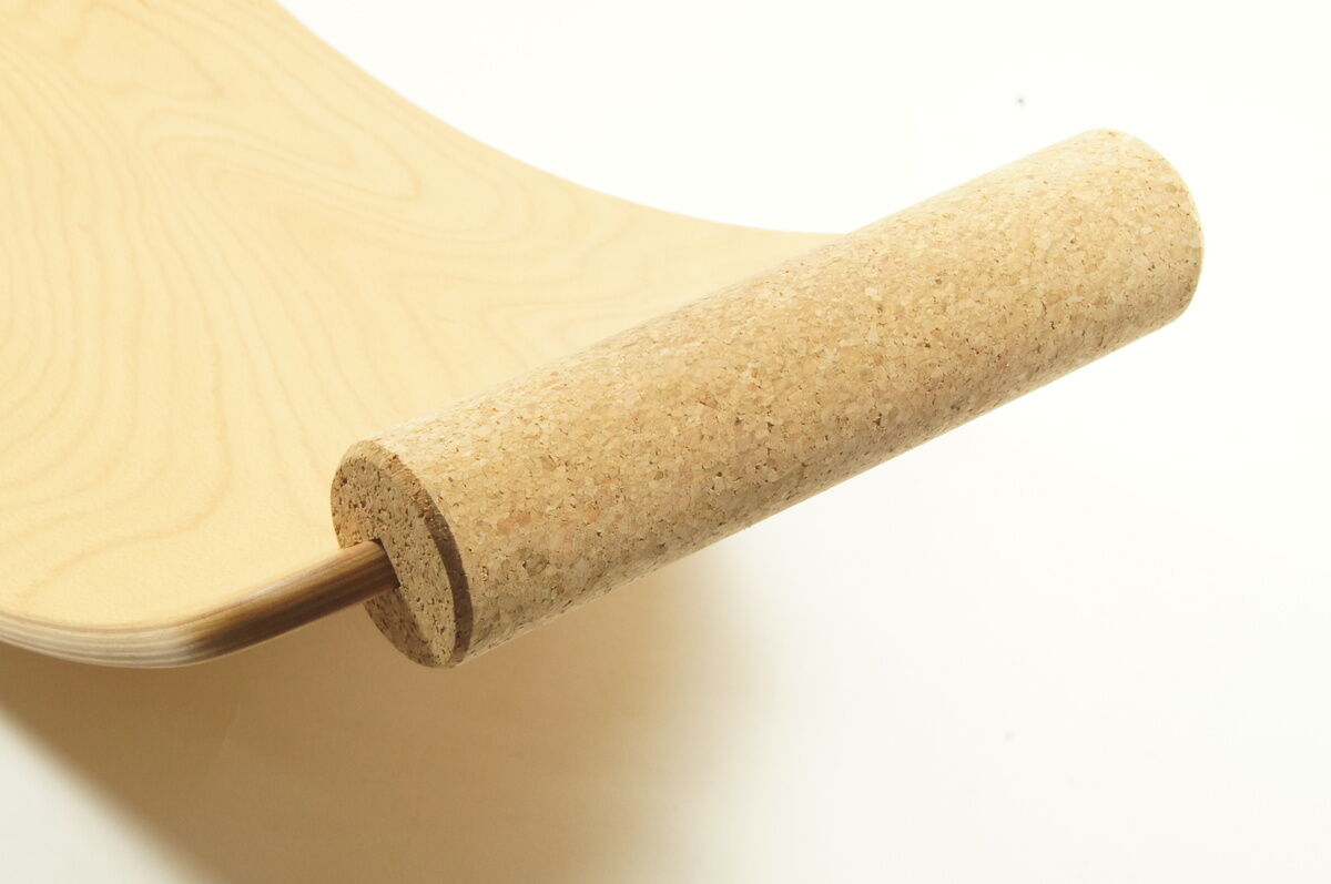 Das Bild zeigt eine Holzplatte eines Balance Boards und eine zylindrische Rolle aus Kork, die auf einer weißen Oberfläche liegt.