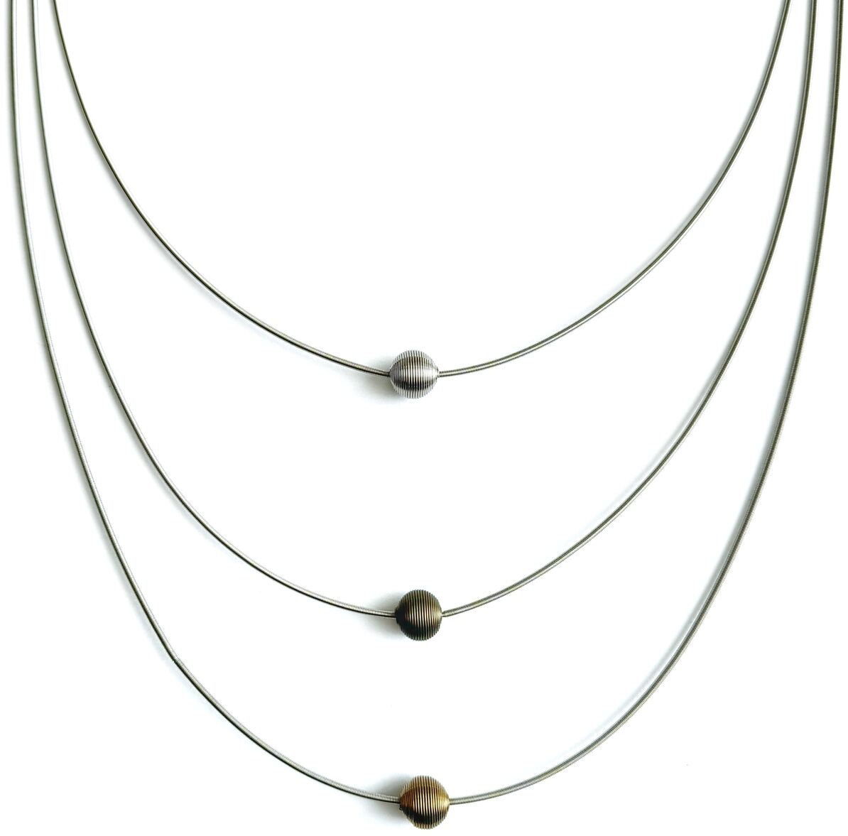 Dreilagige Halskette mit drei runden Perlen in Silber und Gold. Jeder Strang hat eine einzelne schlichte Perle, die auf dünnen, silberfarbenen Ketten hängt. Die Kette ist minimalistisch und elegant gestaltet.