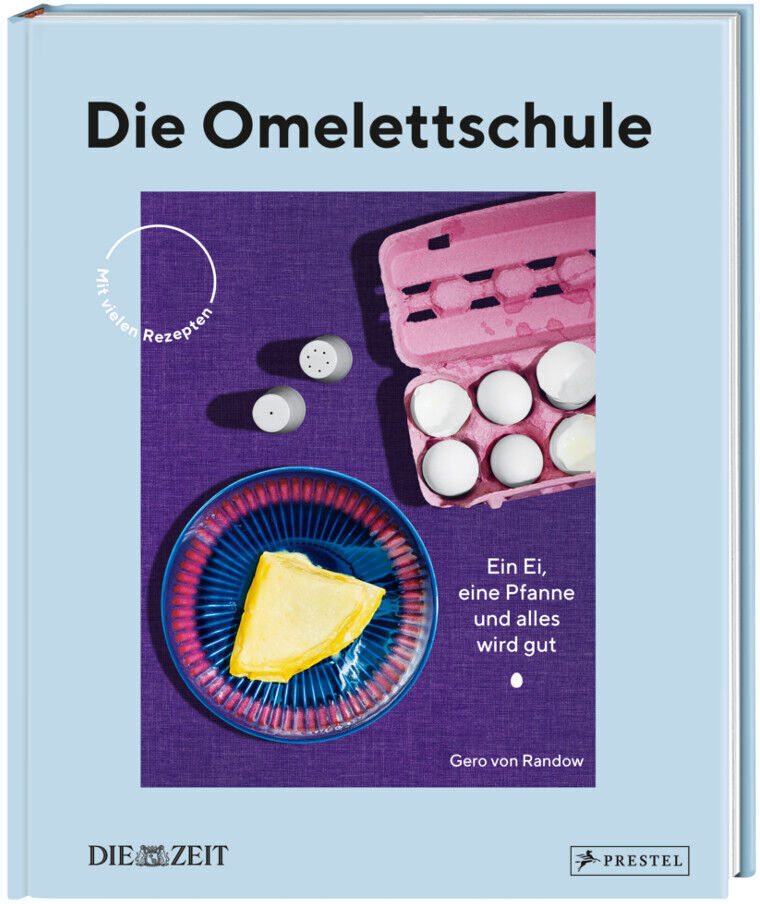 Das Bild zeigt das Kochbuch 'Die Omelettschule' von Gero von Randow, herausgegeben von Die Zeit und Prestel. Auf dem hellblauen Cover ist ein Teller mit einem Omelett abgebildet, zusammen mit einem Karton Eier.