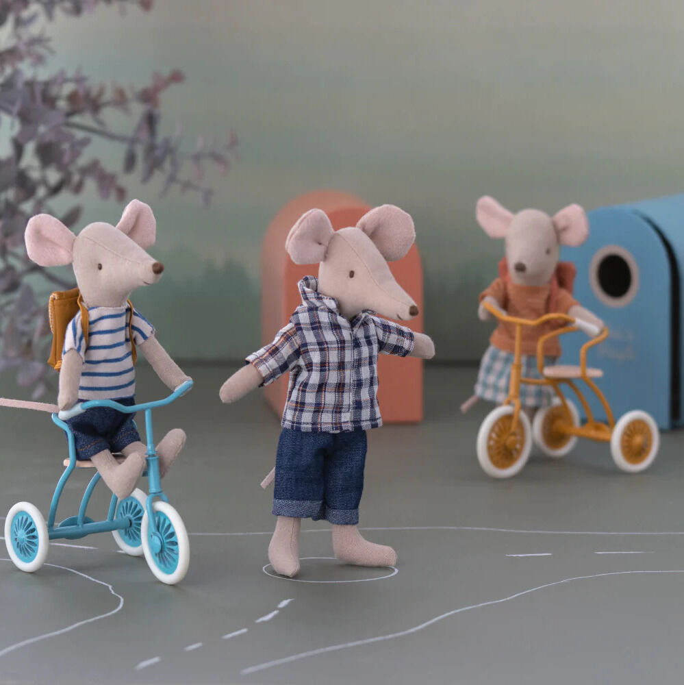 Drei Stoffspielzeugmäuse auf Fahrrädern in einer liebevoll gestalteten Szene mit pastellfarbenem Hintergrund. Eine Maus trägt ein kariertes Hemd und hat eine kleine Tasche auf dem Rücken.