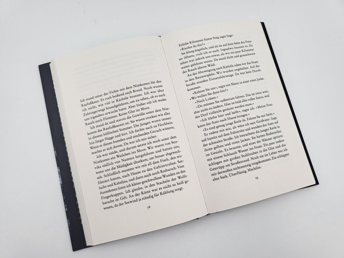 Ein geöffnetes Buch mit Text auf beiden Seiten. Der Text ist in deutscher Sprache geschrieben und das Buch hat eine schwarze Umrandung.