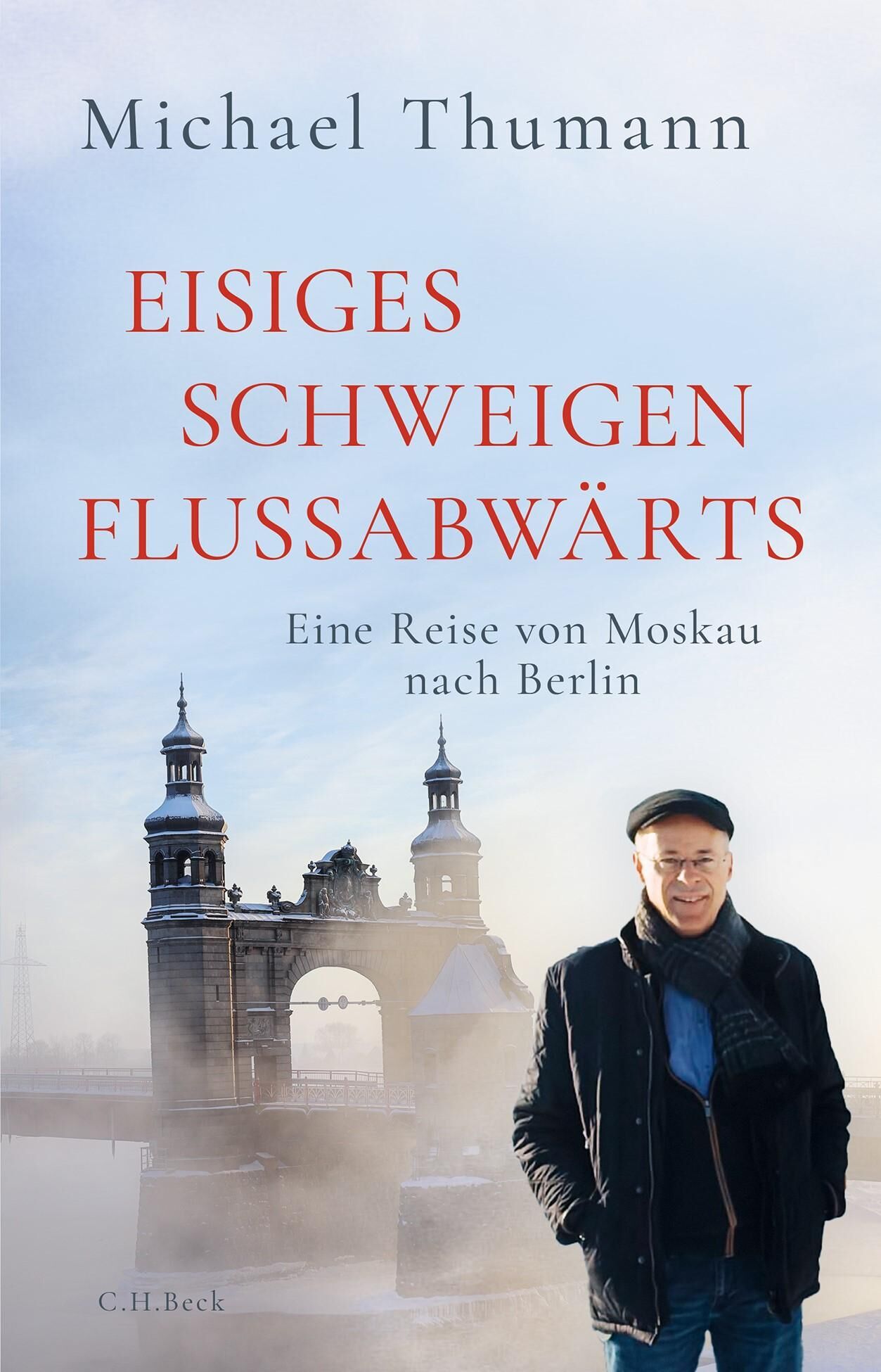 Buchcover mit dem Titel 'Eisiges Schweigen flussabwärts' von Michael Thumann. Im Vordergrund steht ein Mann vor einer winterlichen Flusslandschaft mit einer historischen Steinbrücke und Nebel im Hintergrund. Die Farben sind überwiegend hellblau, weiß und grau.