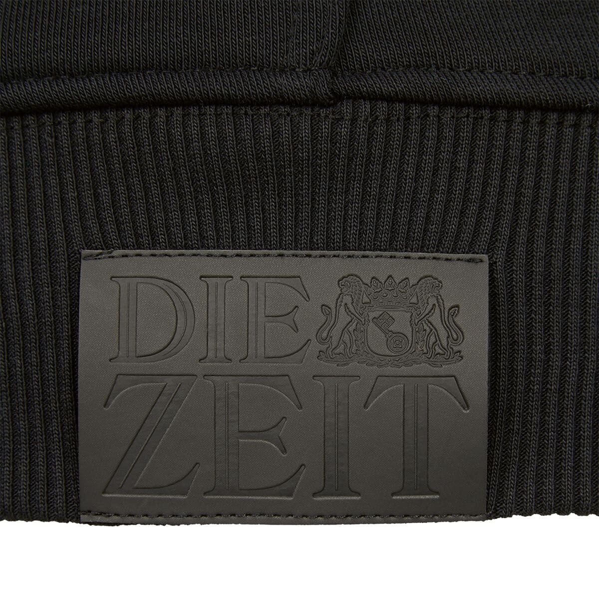 Nahaufnahme eines schwarzen Hoodies aus der ZEIT-Kollektion mit einem geprägten 'DIE ZEIT'-Logo und zwei Löwen darüber.