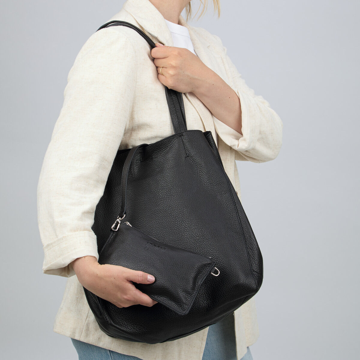 Eine Frau trägt die ZEIT-Tasche »Cep« Schwarzbraun von Guerer & Guerer am Schulterriemen. Die Tasche besteht aus hochwertigem, schwarzbraunem, leicht glänzendem Rindsleder und besitzt eine kleine Innentasche mit Reißverschluss in gleicher Farbe. Schlichtes, elegantes Design.