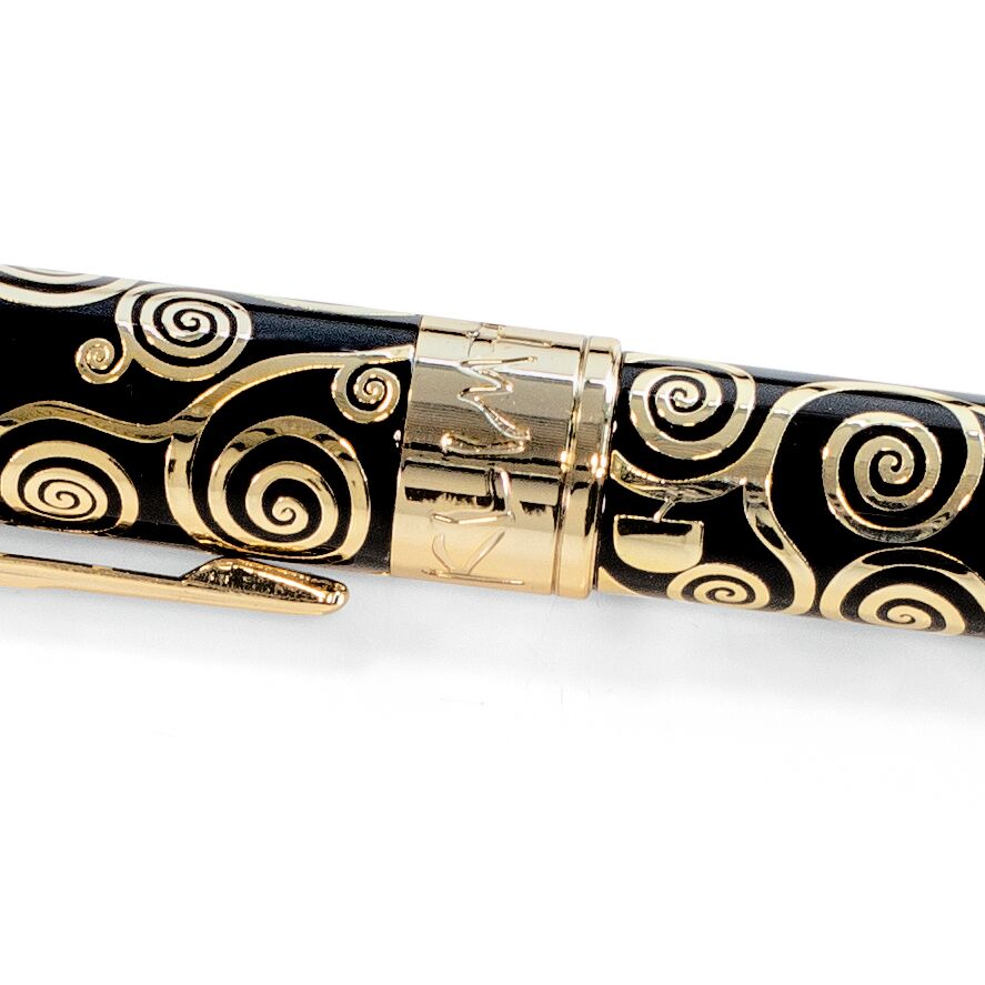 Detailansicht eines eleganten Kugelschreibers mit schwarzer Oberfläche und goldfarbenen, kunstvollen Spiralmustern im Stil von Gustav Klimt. In der Mitte ein glänzender goldfarbener Ring mit Gravur. Das Material ist Metall, hochwertig verarbeitet.