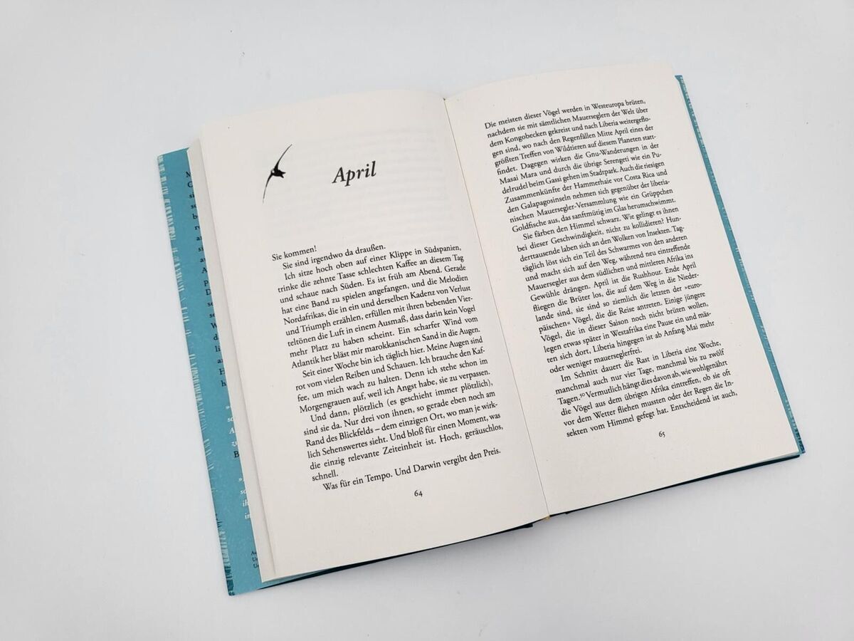 Gezweigtes Buch mit zwei Seiten, die einen Text in deutscher Sprache enthalten, wobei die linke Seite einen Abschnitt mit der Überschrift 'April' zeigt. Der Einband des Buches hat einen hellblauen Rand.