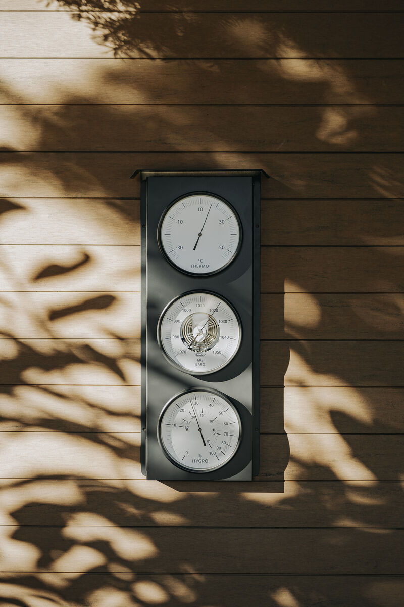 Eine Außenwetterstation der ZEIT-Sonderedition, montiert an einer Holzwand, die Temperatur, Luftfeuchtigkeit und Luftdruck anzeigt.