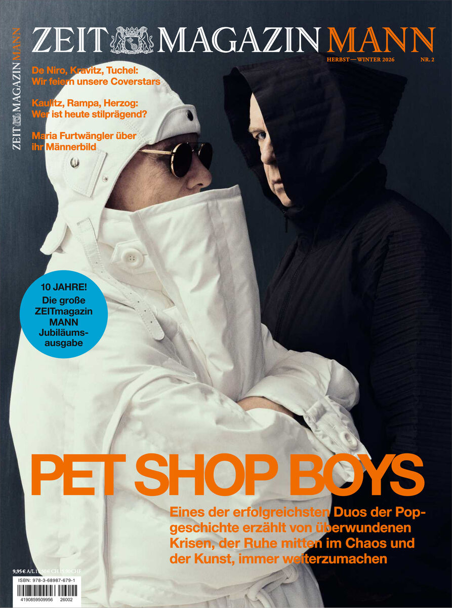 Titelbild des ZEITmagazin MANN 2/26 zeigt die Pet Shop Boys. Ein Mann in weißem Anzug mit Kapuze und Sonnenbrille steht neben einem Mann in schwarzem Hoodie vor dunklem Hintergrund. Große orange Schrift: PET SHOP BOYS. Text mit weiteren Themen des Magazins.