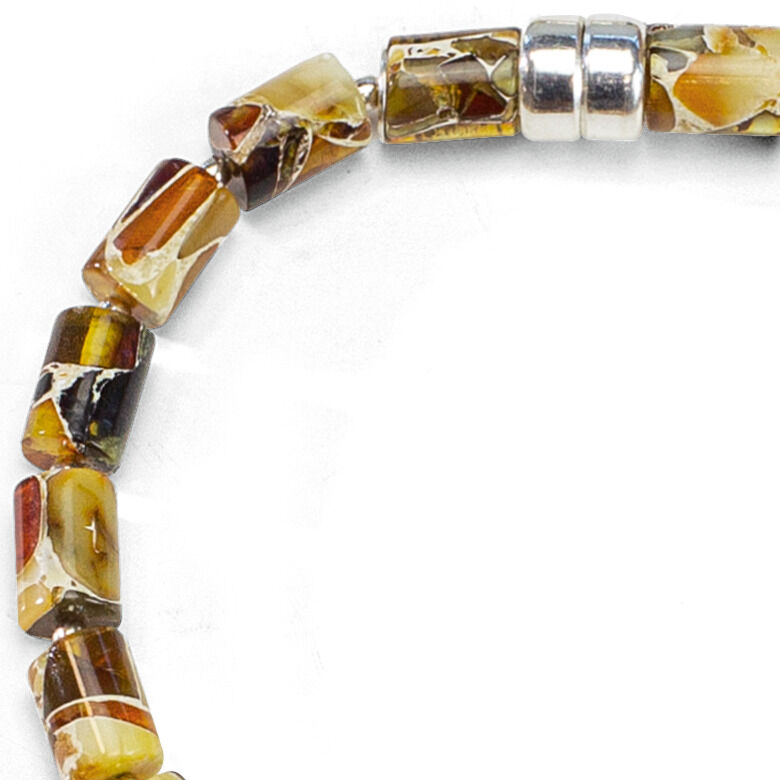Detailaufnahme eines Armbands aus dem Bernstein-Schmuckset "Jantara" von Ars mundi. Das Armband besteht aus facettierten, naturfarbenen Bernsteincylindern und drei silbernen Zwischenelementen. Die Rottöne und Gelbtöne wirken warm und sind einzigartig gemustert.